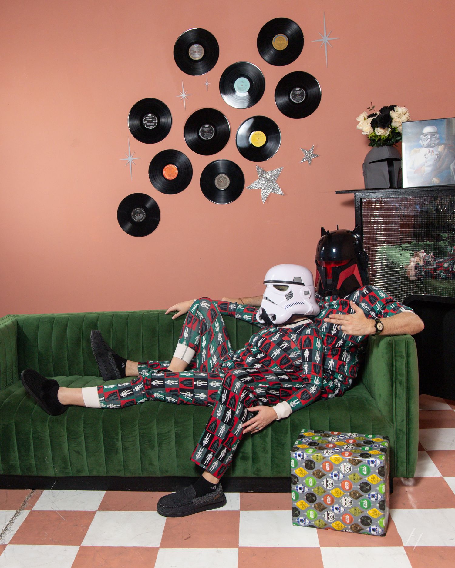 Star Wars Stormtrooper and Boba Fett helmets displayed on a green velvet couch with vinyl records on the coral wall.