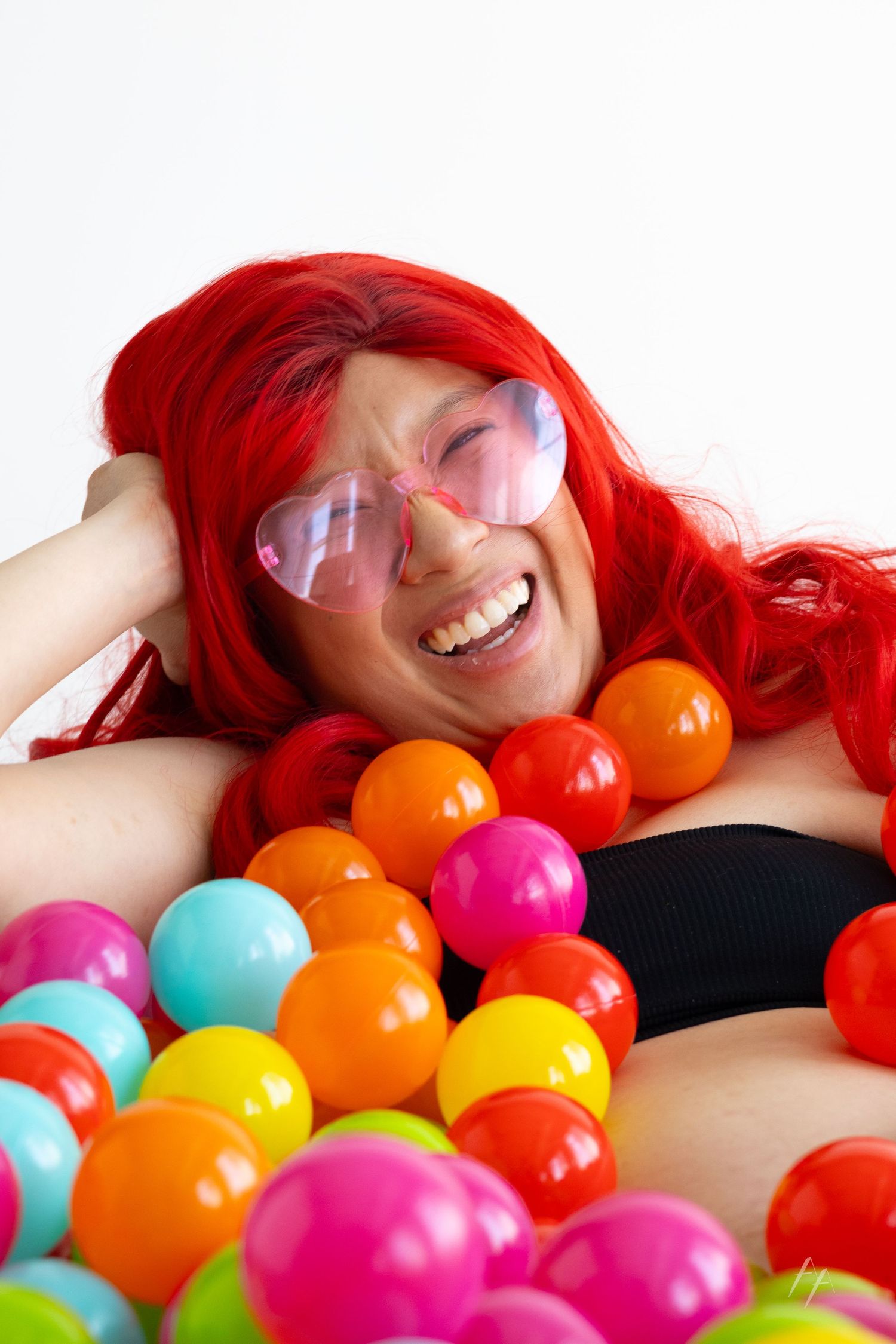 Weird maternity portraits of woman in bathtub of rainbow balls at Denver Photo Collective