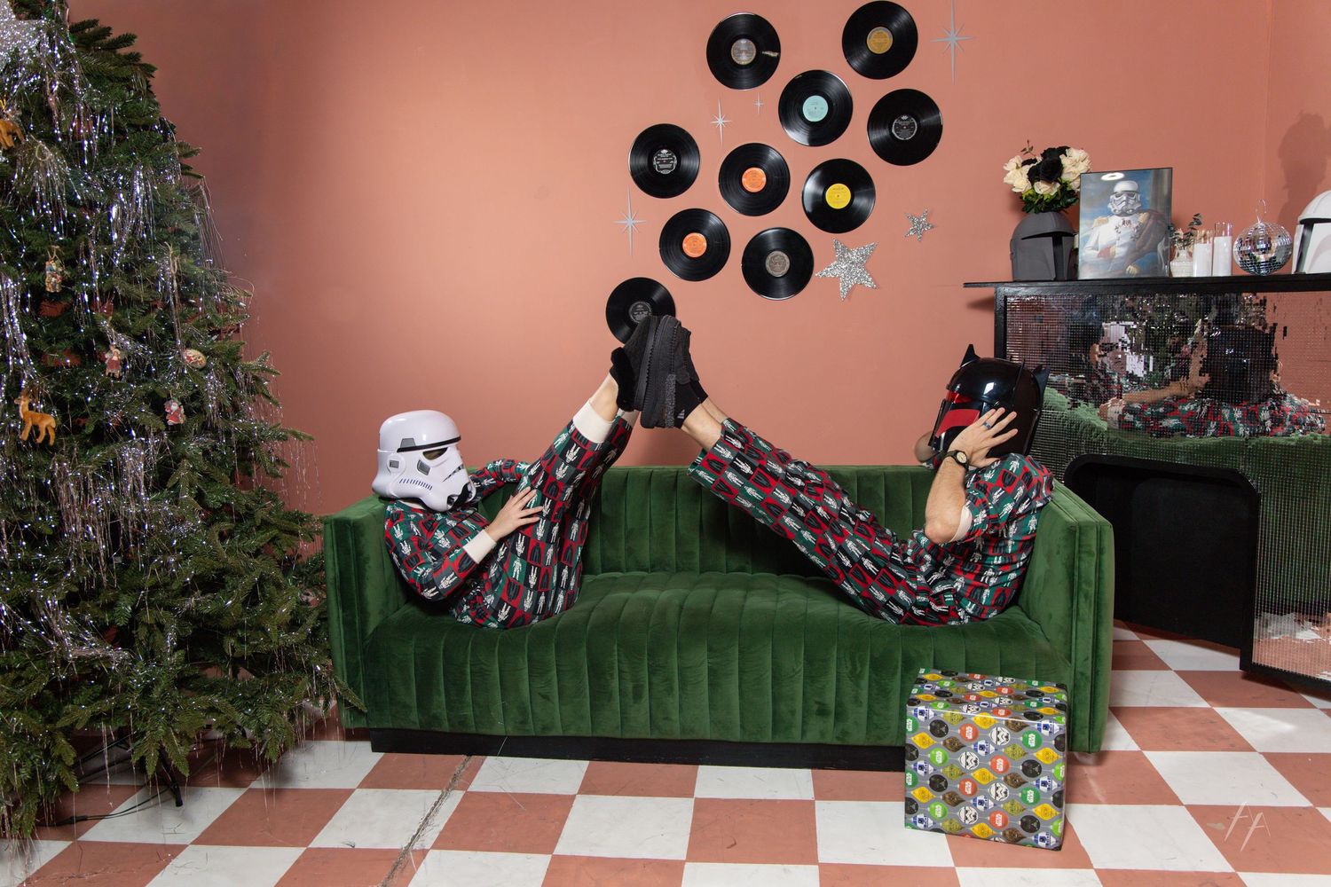 Star Wars Holiday Portraits with Green velvet sofa decorated with holiday pillows next to a Christmas tree and vinyl records on a pink wall.