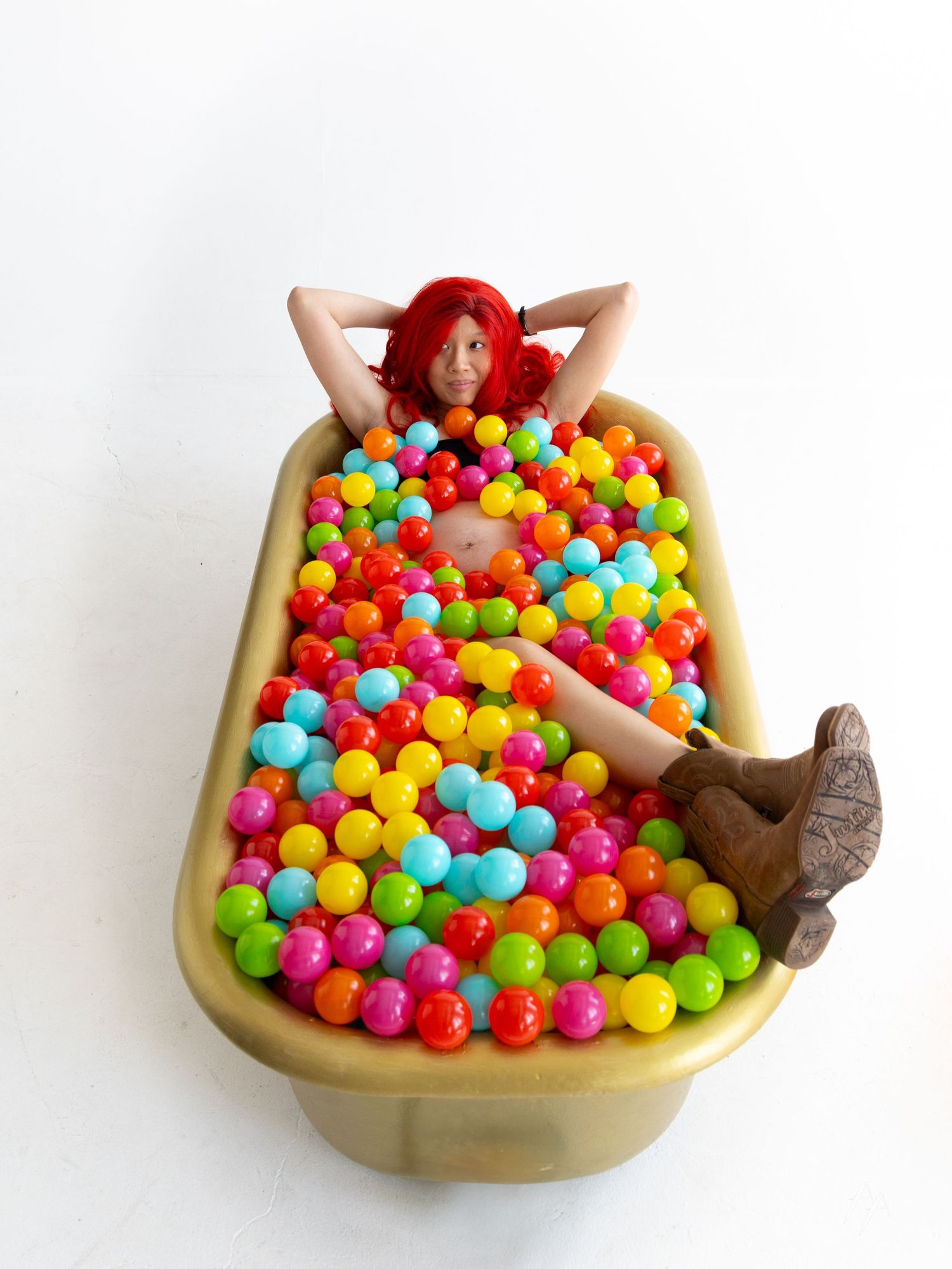Weird maternity portraits of woman in bathtub of rainbow balls at Denver Photo Collective