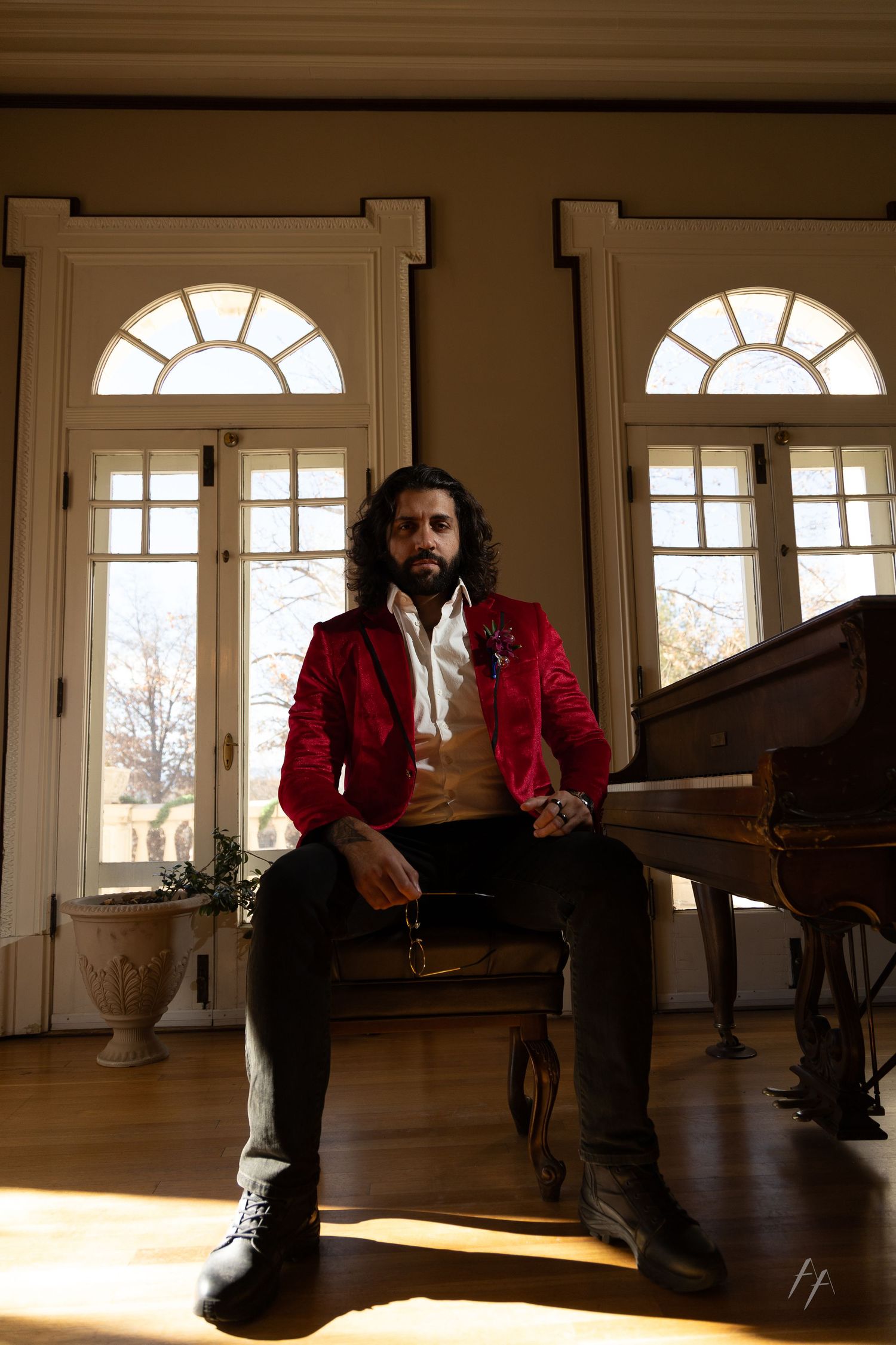 A person in a red blazer sits in various poses near sunlit windows in an elegant room.
