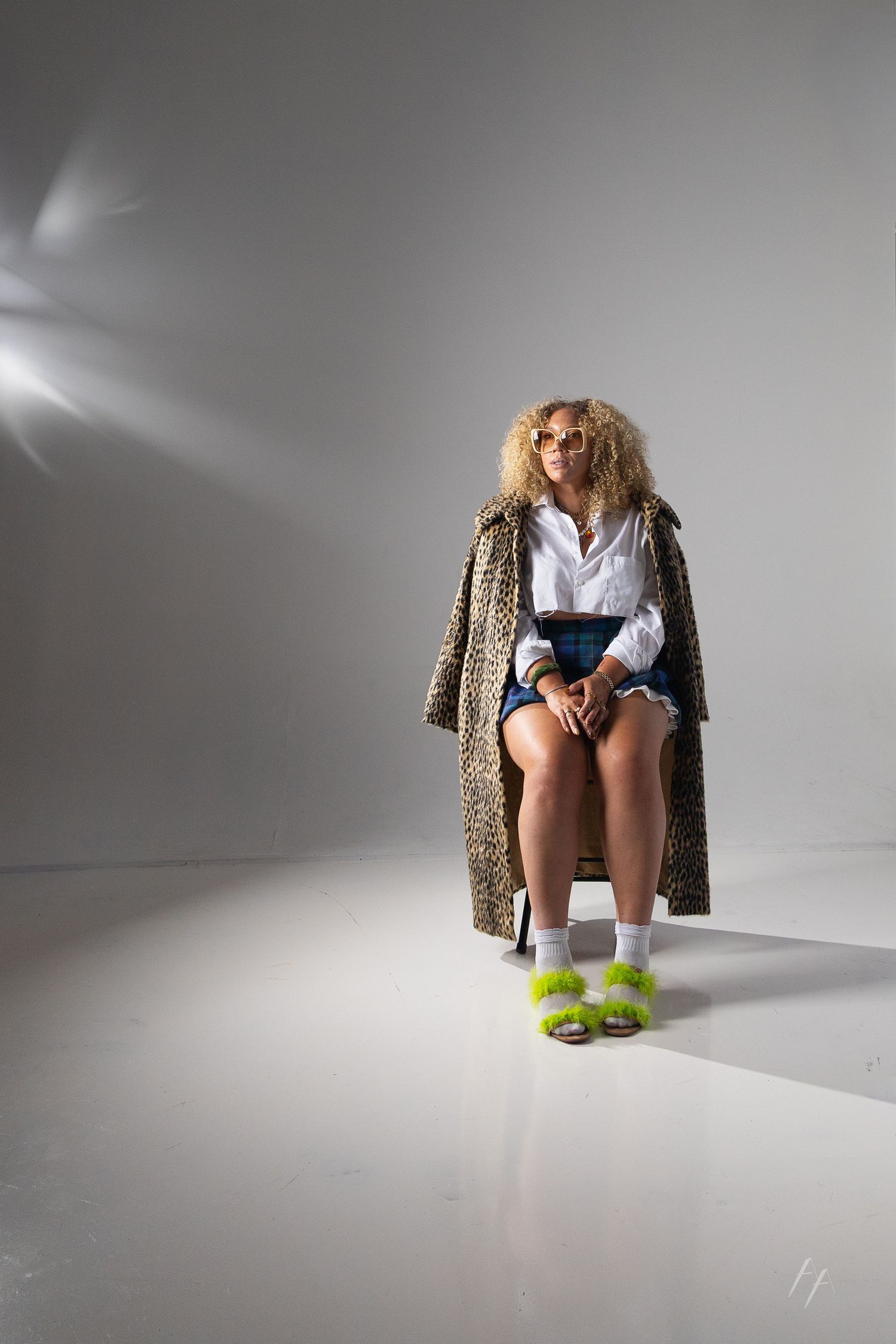 A series of minimalist fashion photos showing someone wearing a leopard print coat and bright yellow slippers against white backdrop.
