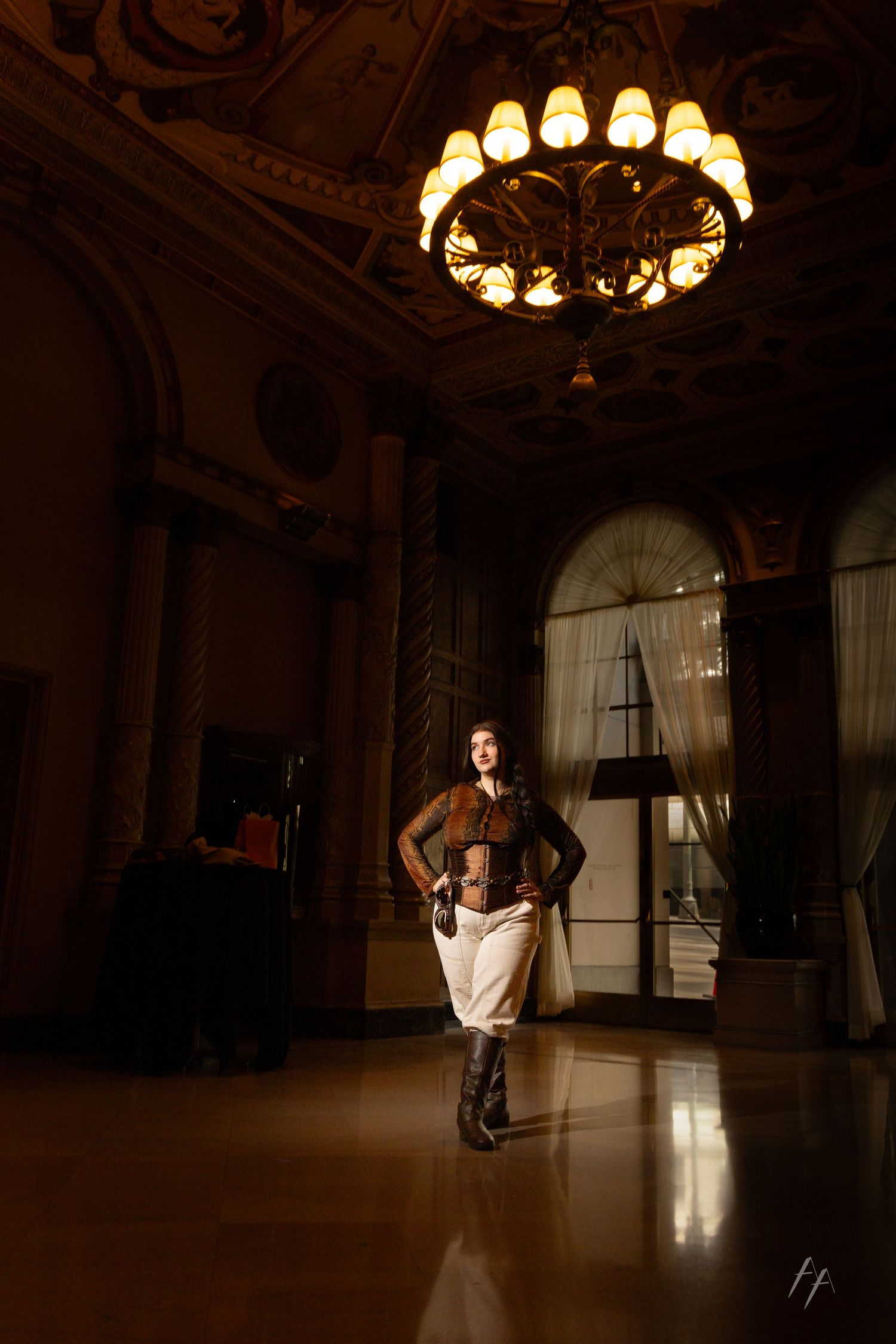 Elegant dance performance in a grand ballroom with ornate chandeliers casting warm light across the polished floor.