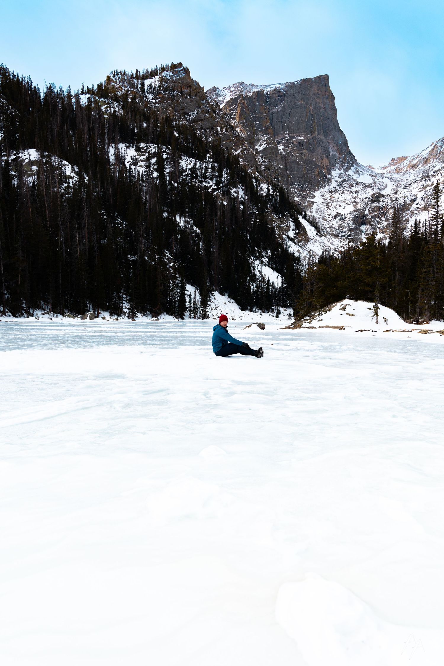 Frozen alpine lake surrounded by snow-capped mountains in winter wilderness.