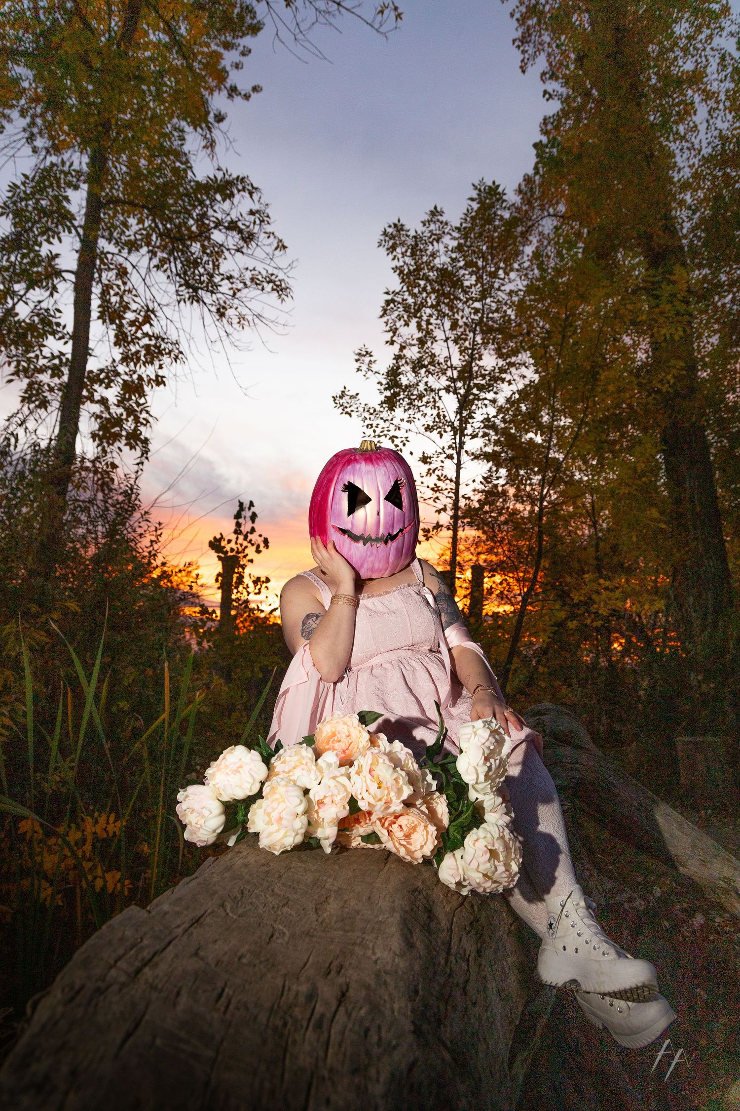 A masked figure in pink with white roses poses against a dramatic sunset and autumn trees. Broomfield Colorado