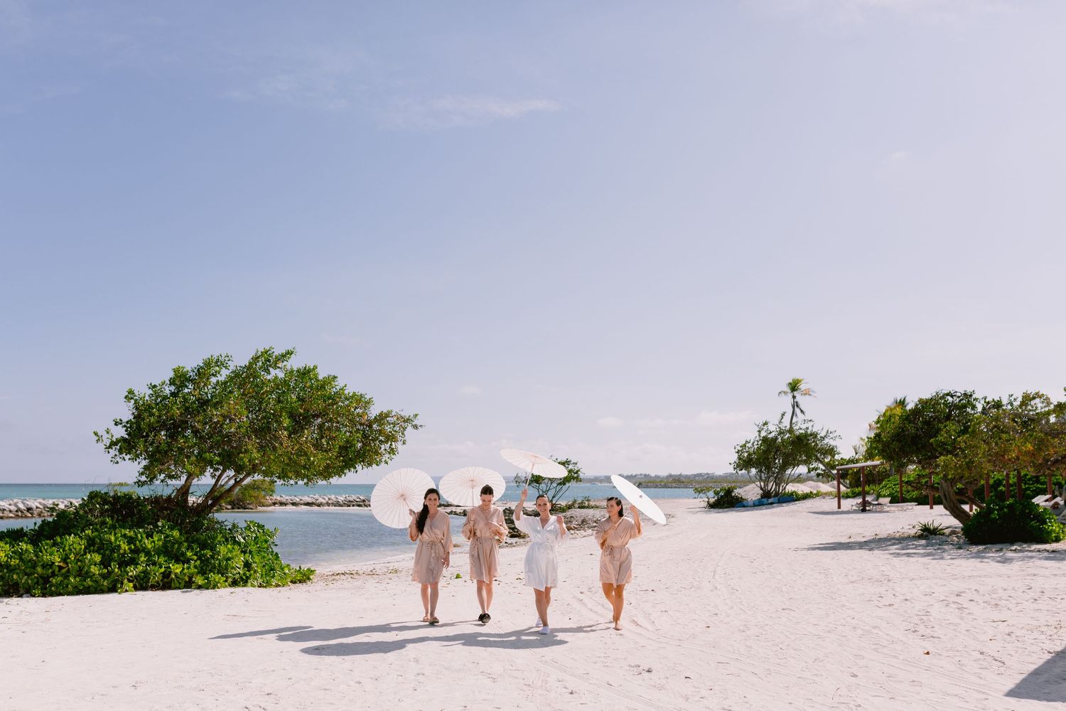 Three people walking together on a white sandy beach with tropical vegetation.