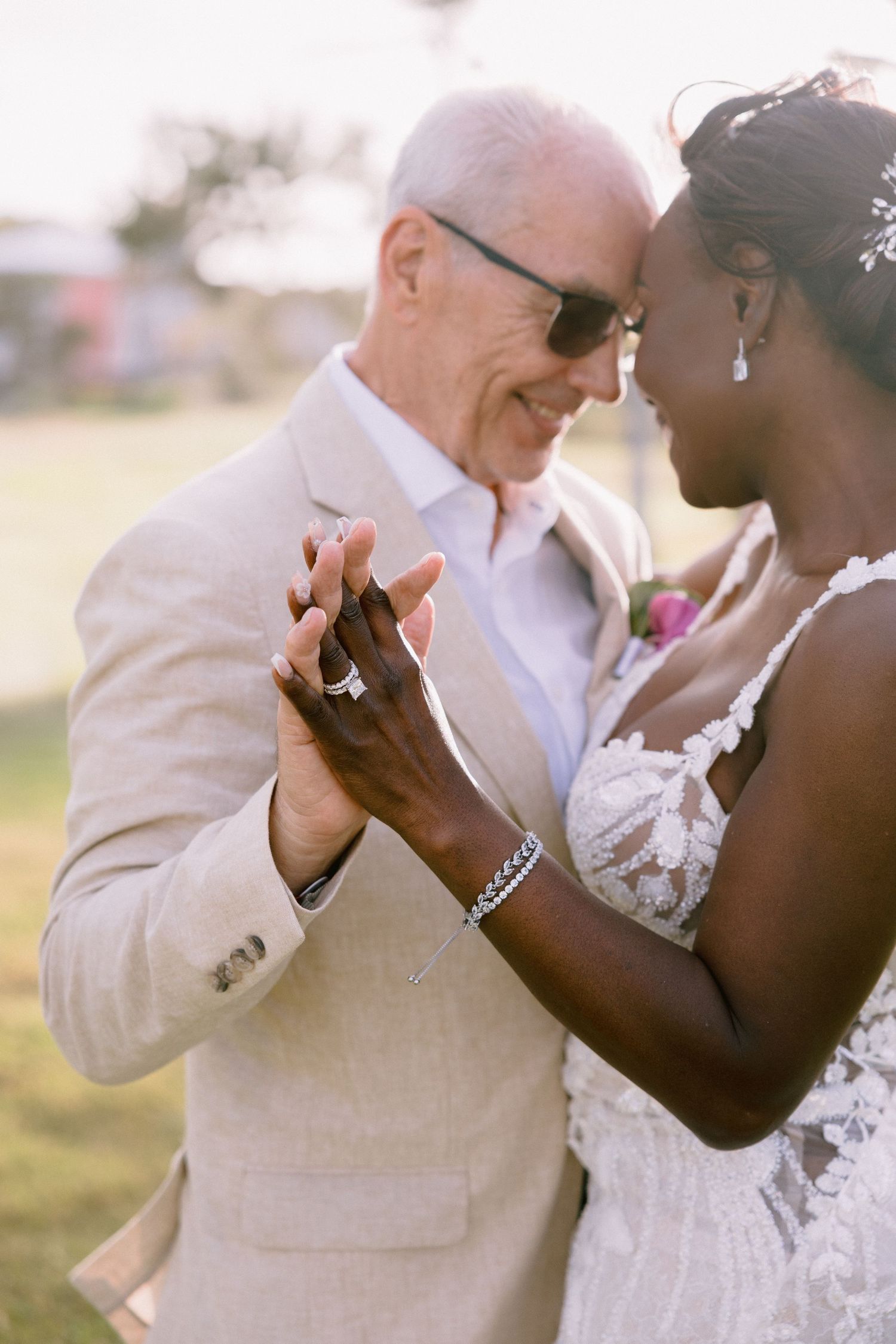A couple shares a tender moment during their outdoor wedding ceremony in white attire.