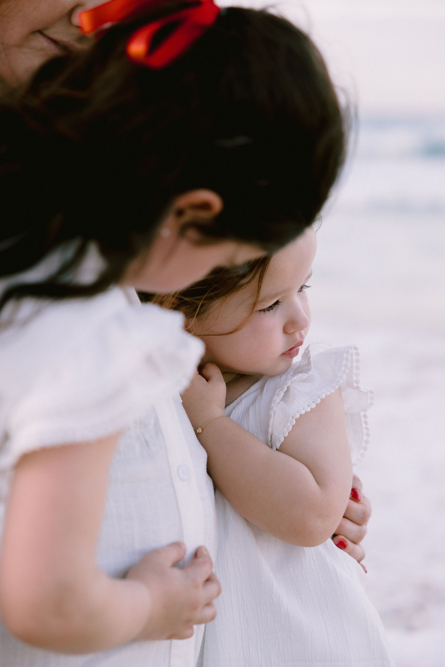 A series of soft, dreamy photos showing a small child in white clothing looking down thoughtfully against a light background.