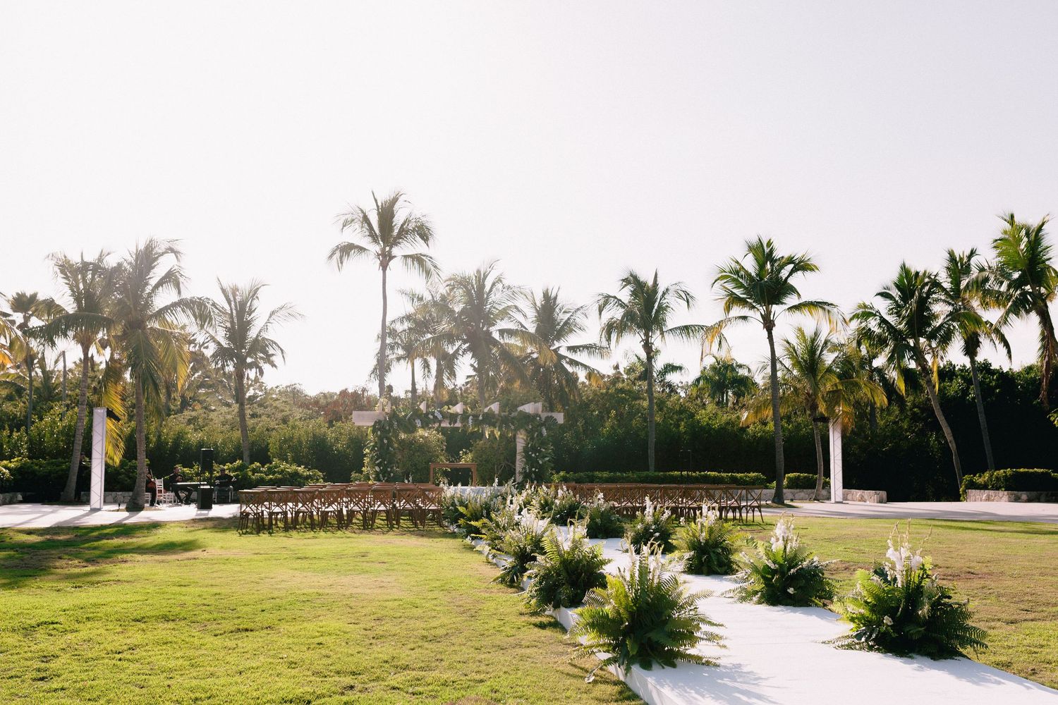 Panoramic view of a golf course with palm trees, lush greens, and bunkers stretching across a tropical landscape.