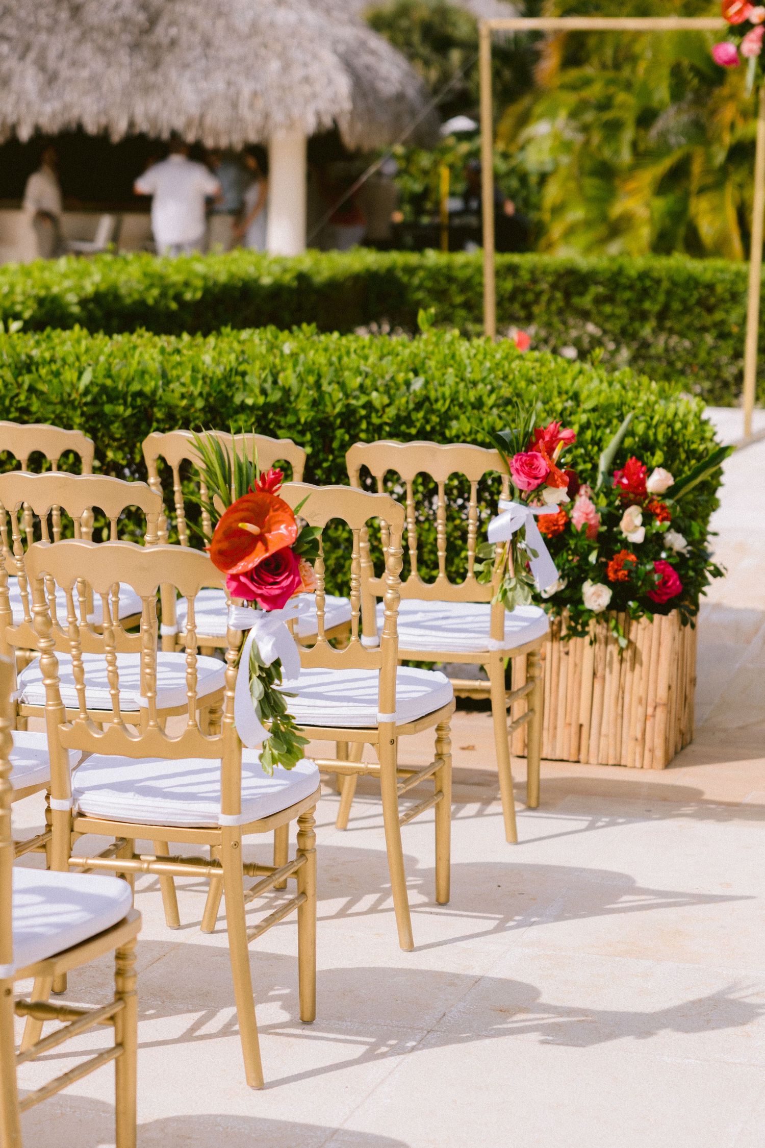 Elegant outdoor wedding reception setup with wooden Chiavari chairs decorated with red and white floral arrangements.