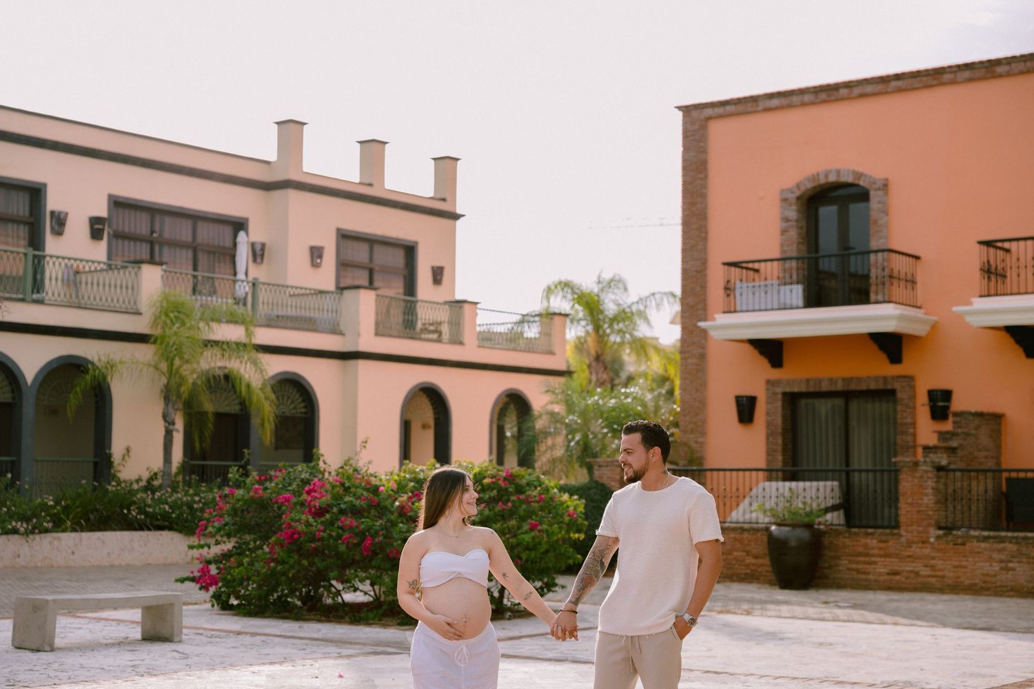 Mediterranean style residential building with terracotta walls and arched doorways surrounded by landscaped gardens.