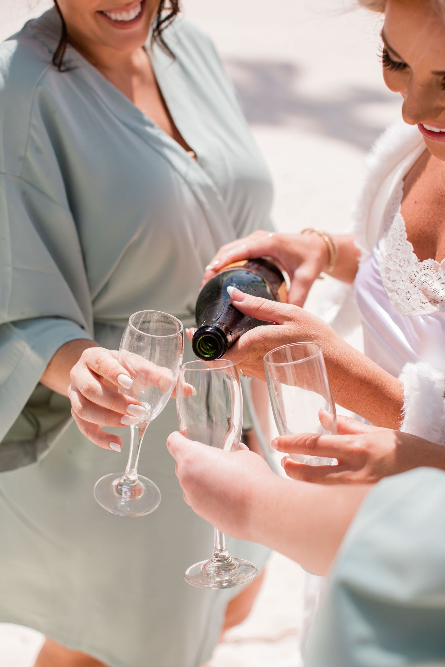 People pouring champagne into glasses during a celebration in soft natural lighting.