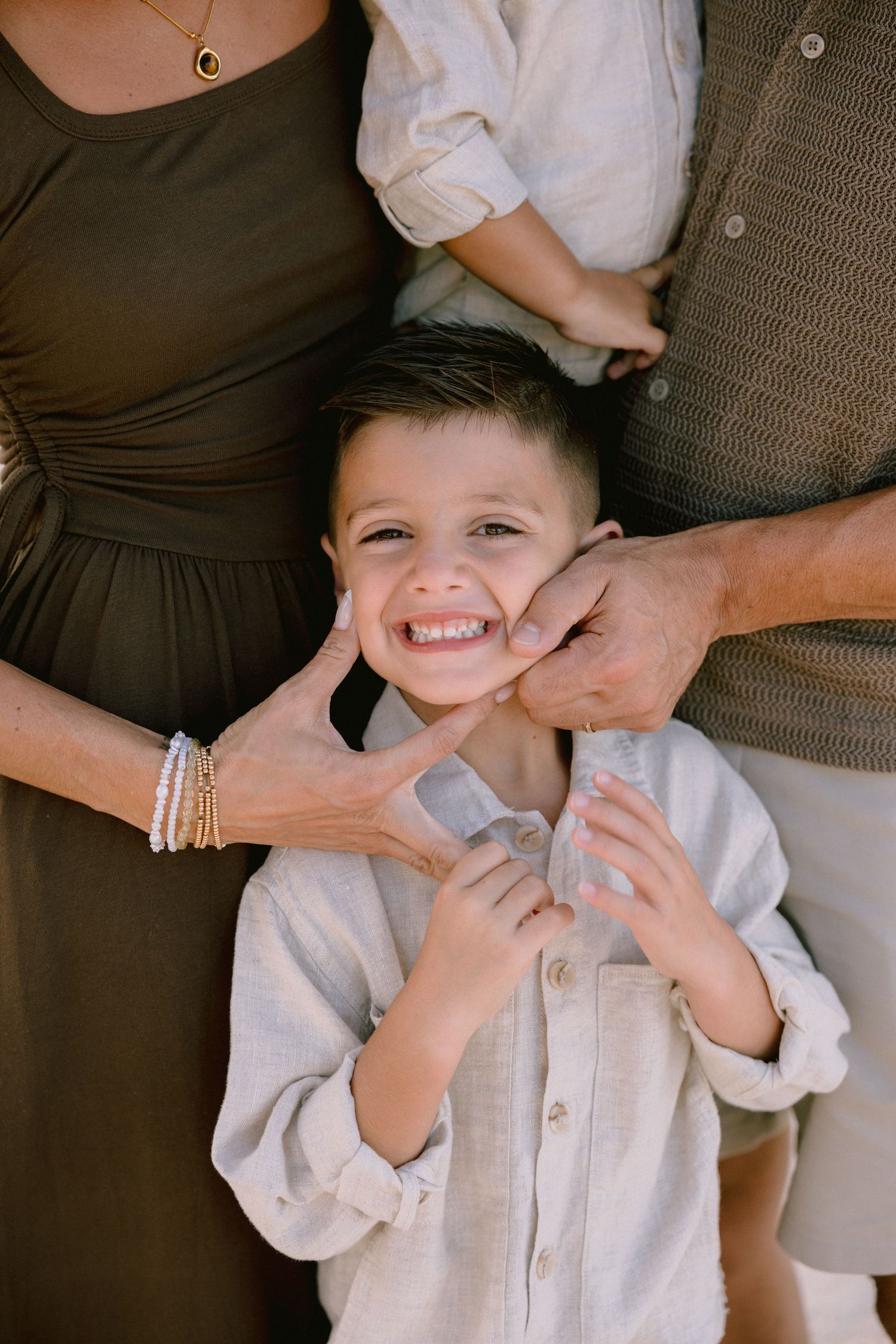 A series of candid photos showing playful interaction between hands and a child wearing a white button-up shirt.