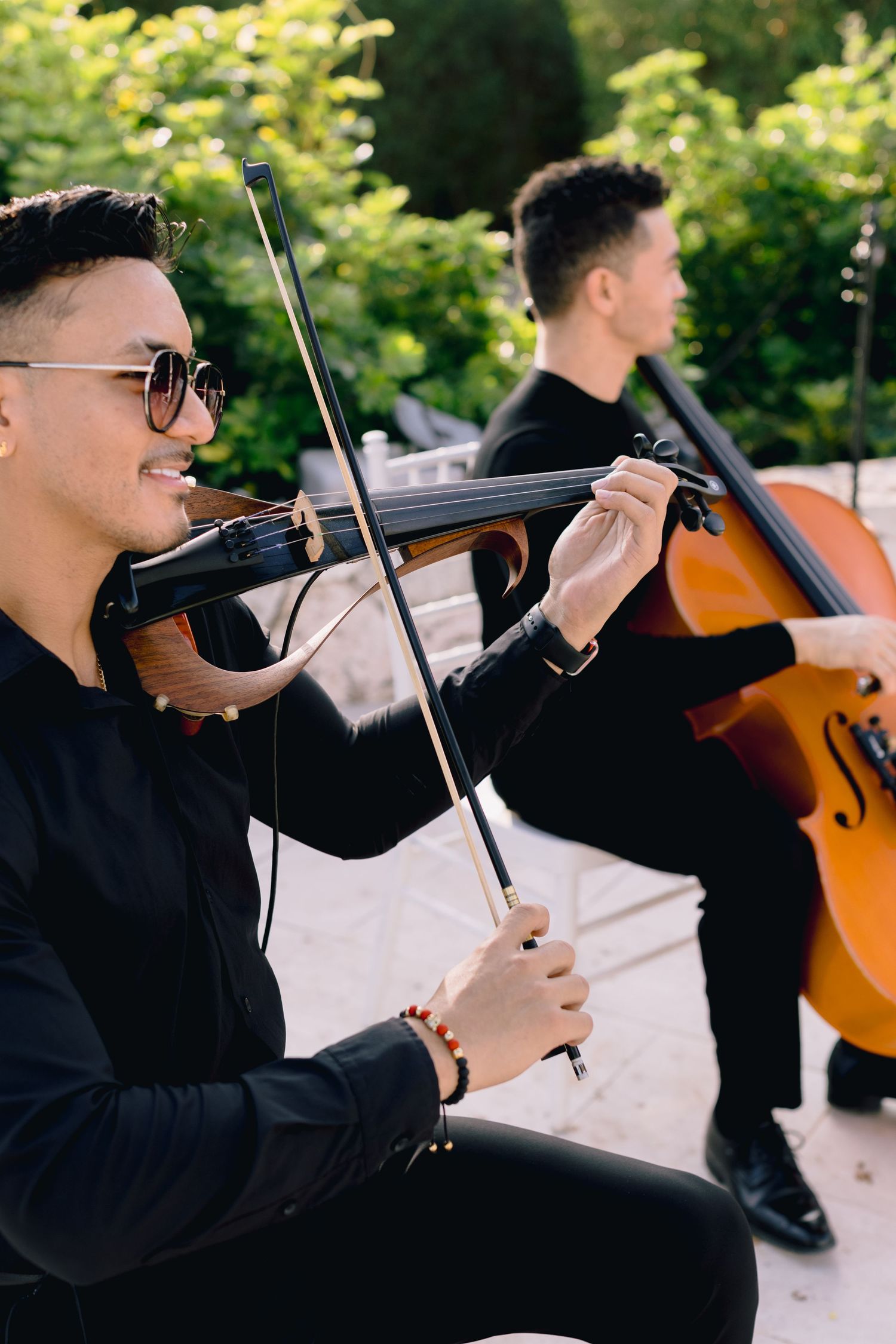 Musicians perform classical music outdoors with violin and cello during a daytime concert.