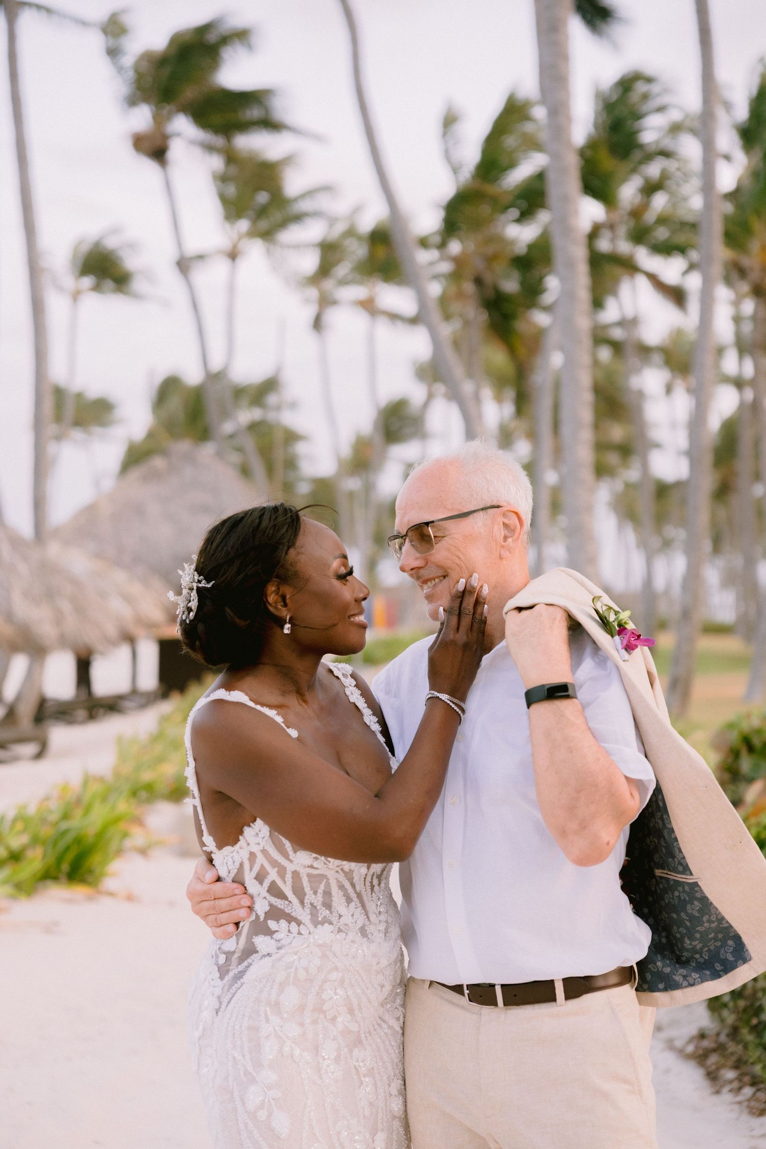 A loving couple shares tender moments while dancing on a tropical beach lined with palm trees.
