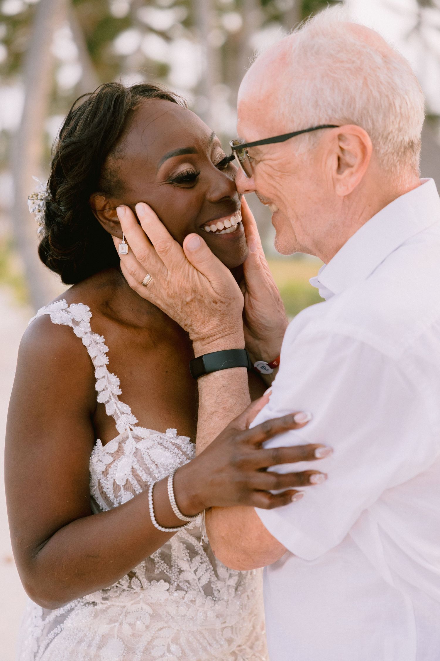 A tender moment between two people embracing, with one wearing a beautiful white lace wedding dress and bracelets.