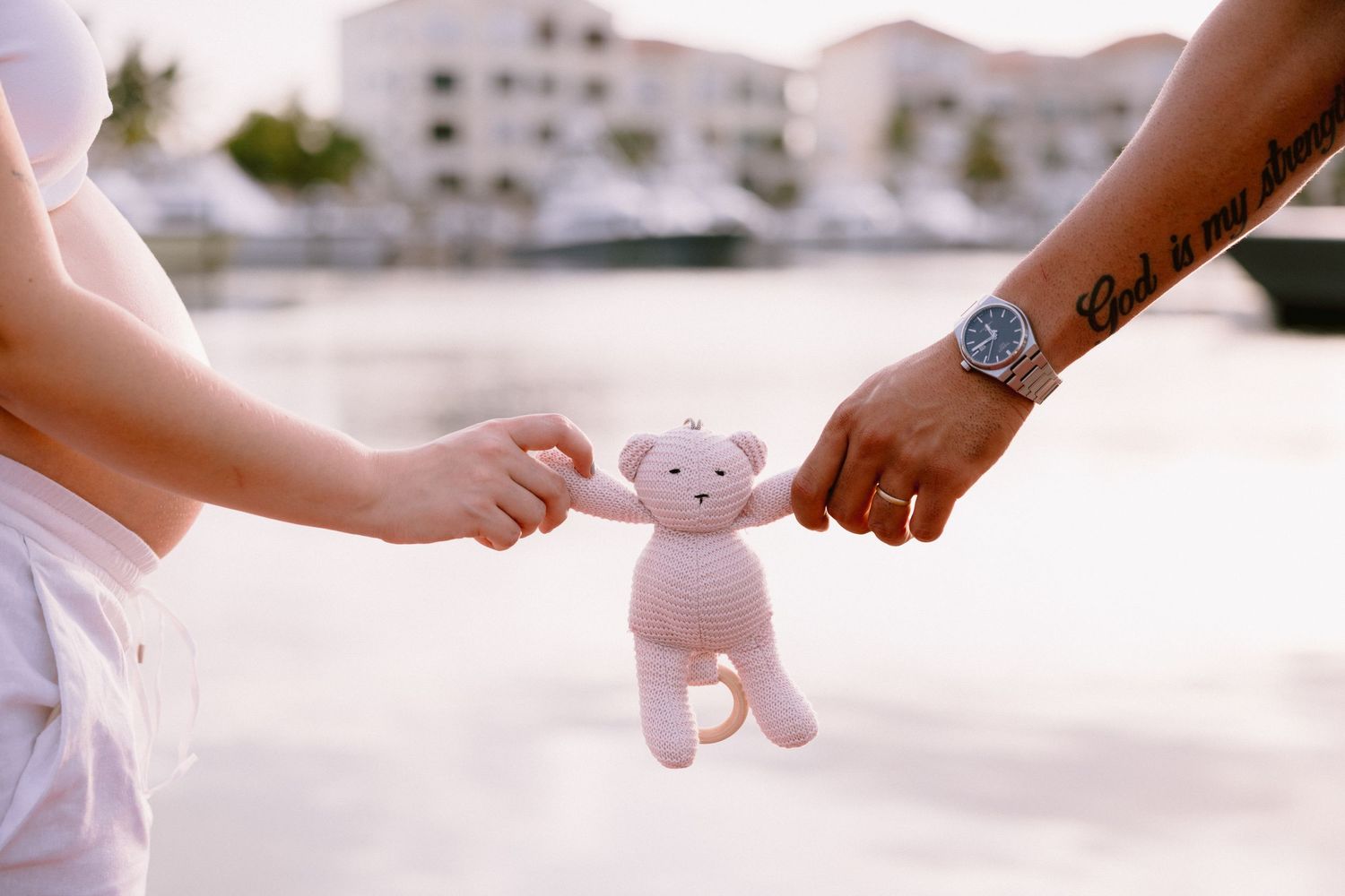 Hands passing a small stuffed animal toy in sequence against a light background.