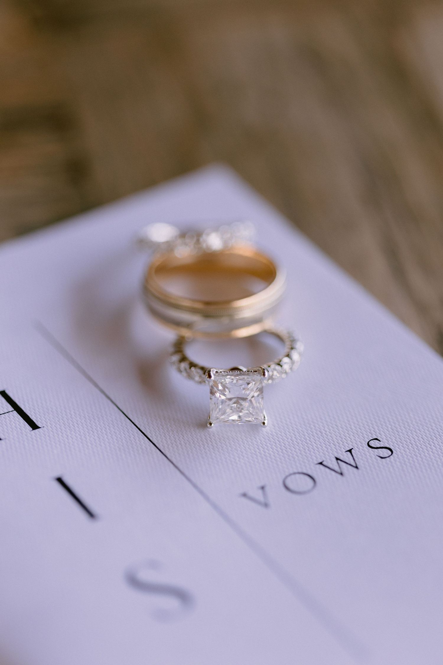 Wedding rings rest on a white lined paper surface showing multiple angles of engagement and wedding band details.