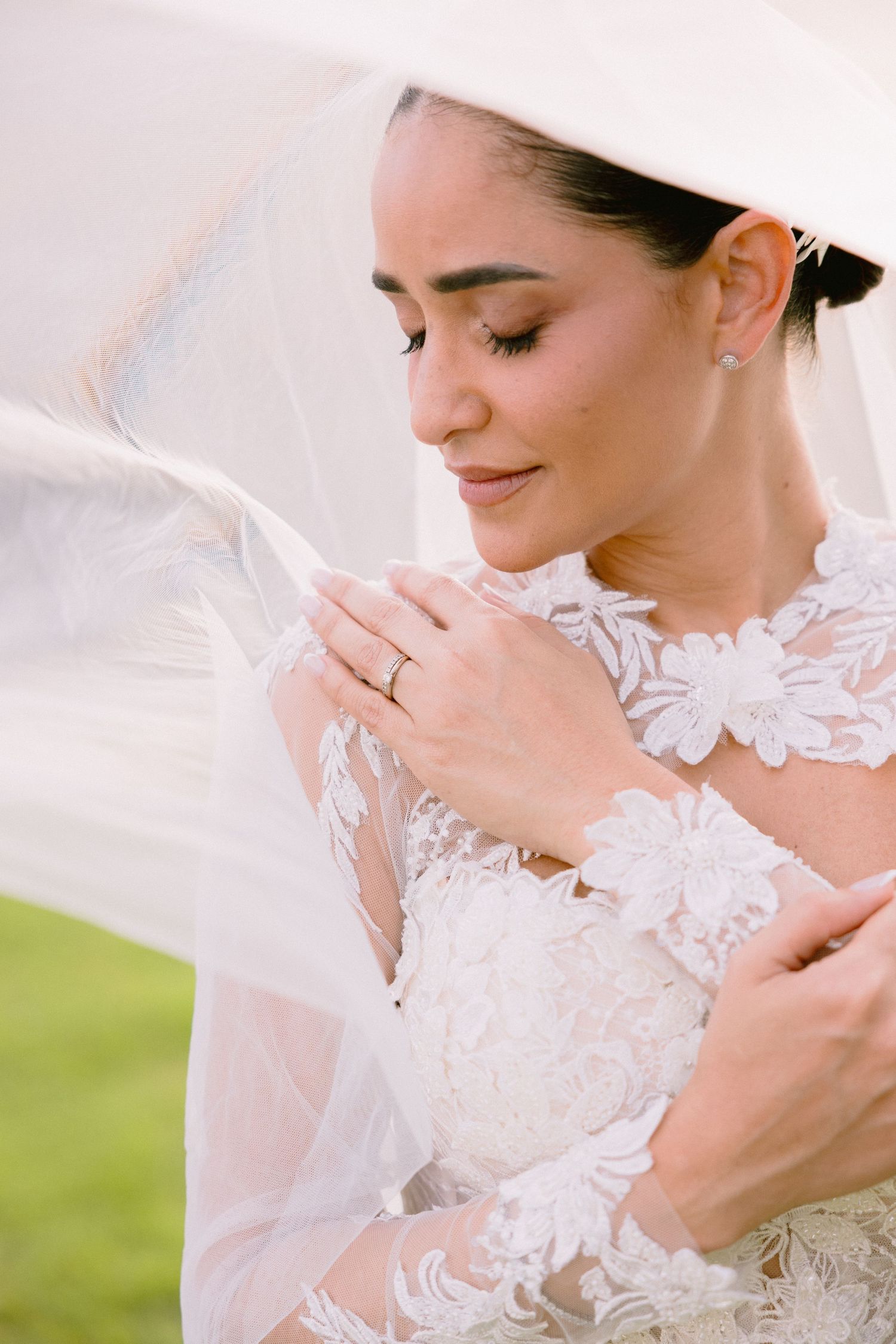 Close-up details of delicate white lace and embroidery on a wedding dress with soft natural lighting.