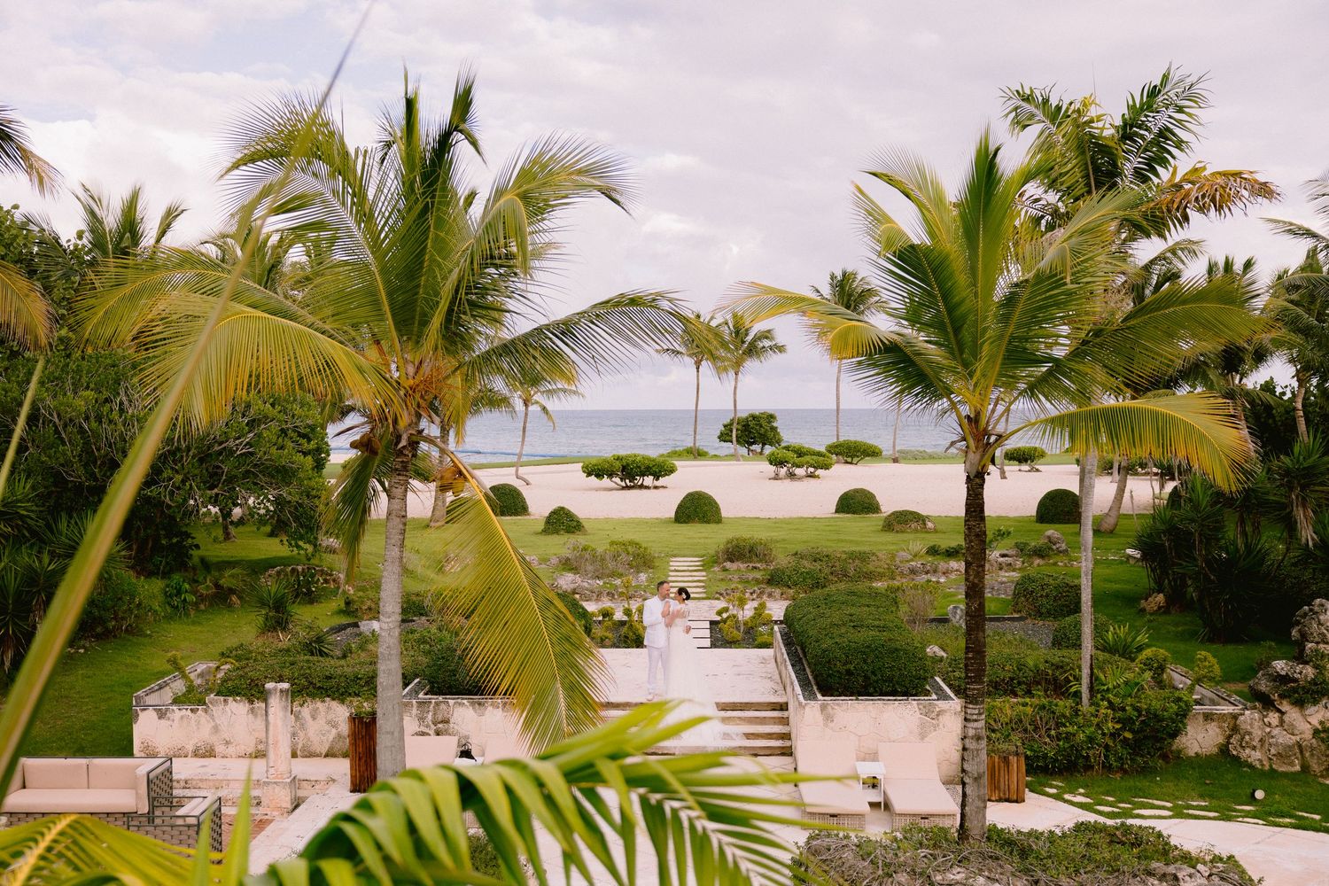 Scenic tropical beach resort with palm trees, white sand, and oceanfront villas stretching along the coastline.