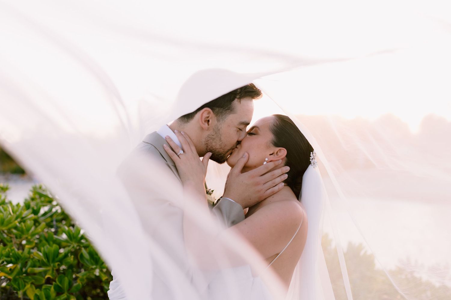 Intimate wedding moment photographed through delicate white veil.