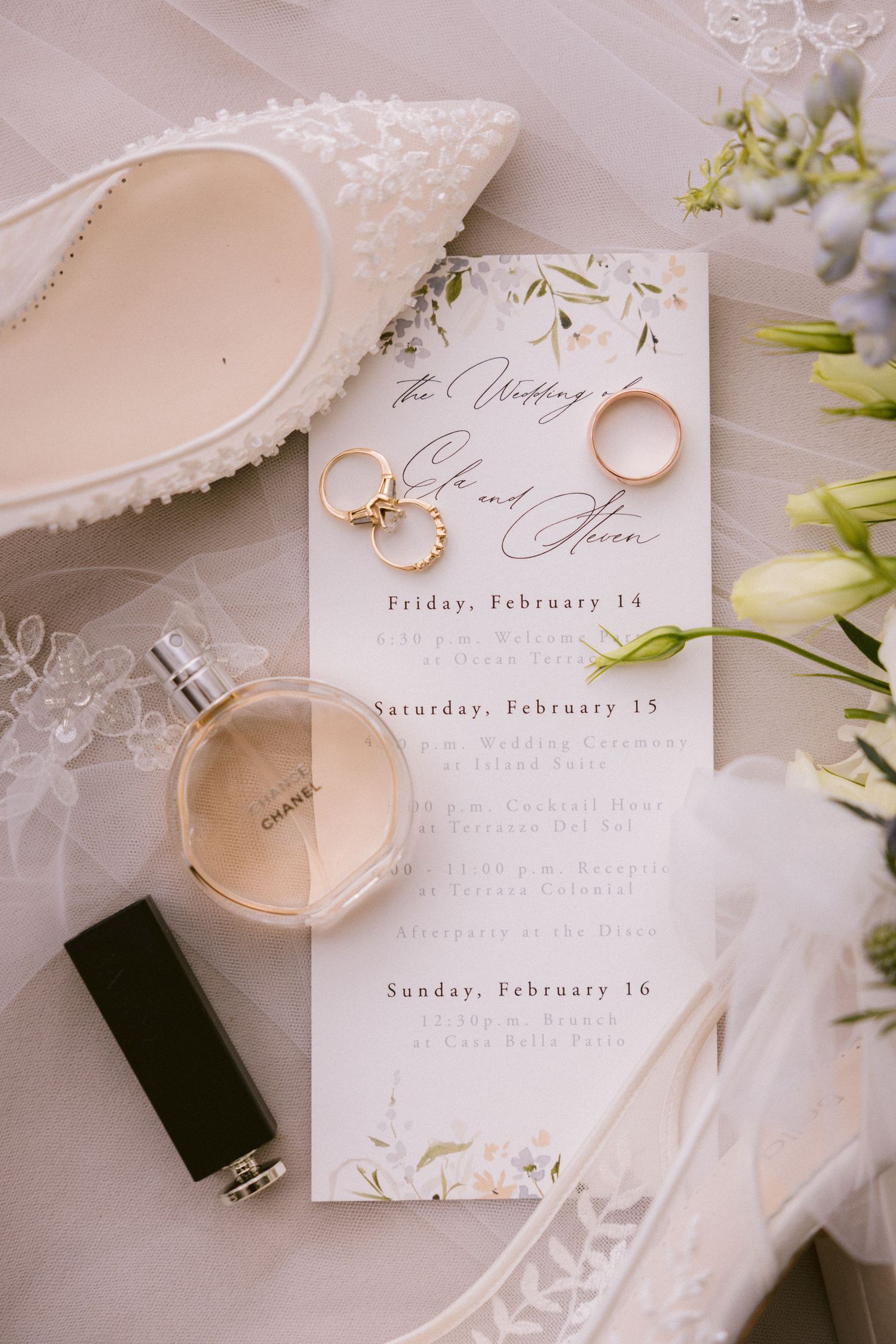 Elegant wedding invitation suite with rings and perfume bottle in neutral tones.