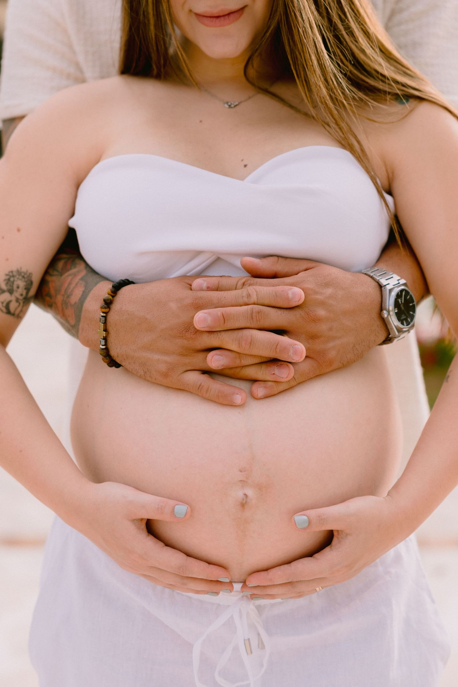 A progressive series of cropped pregnancy photos showing hands cradling a growing baby bump in white attire.