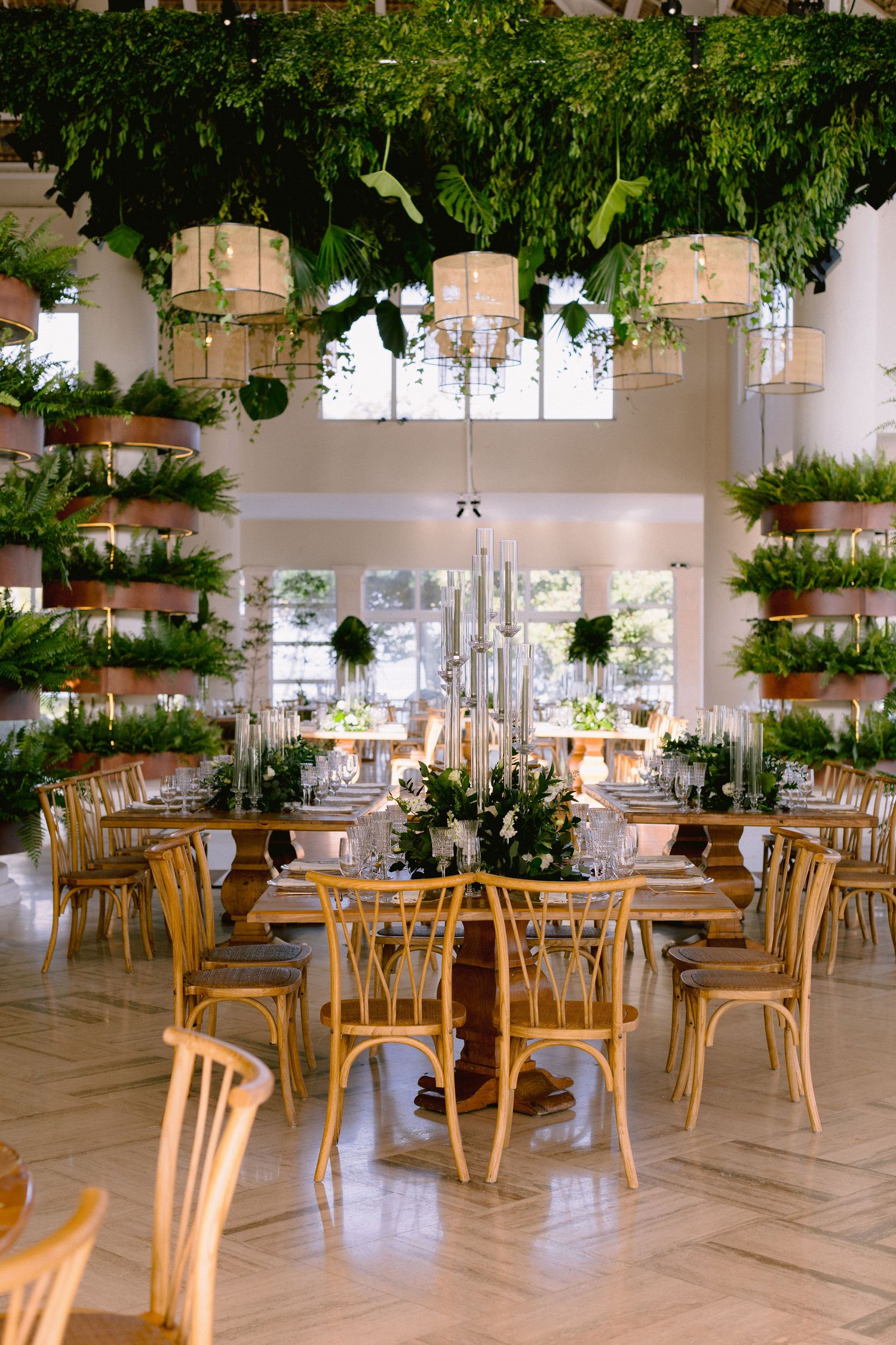 Elegant restaurant interior with wooden chairs and hanging plants creating a bright, airy dining atmosphere.