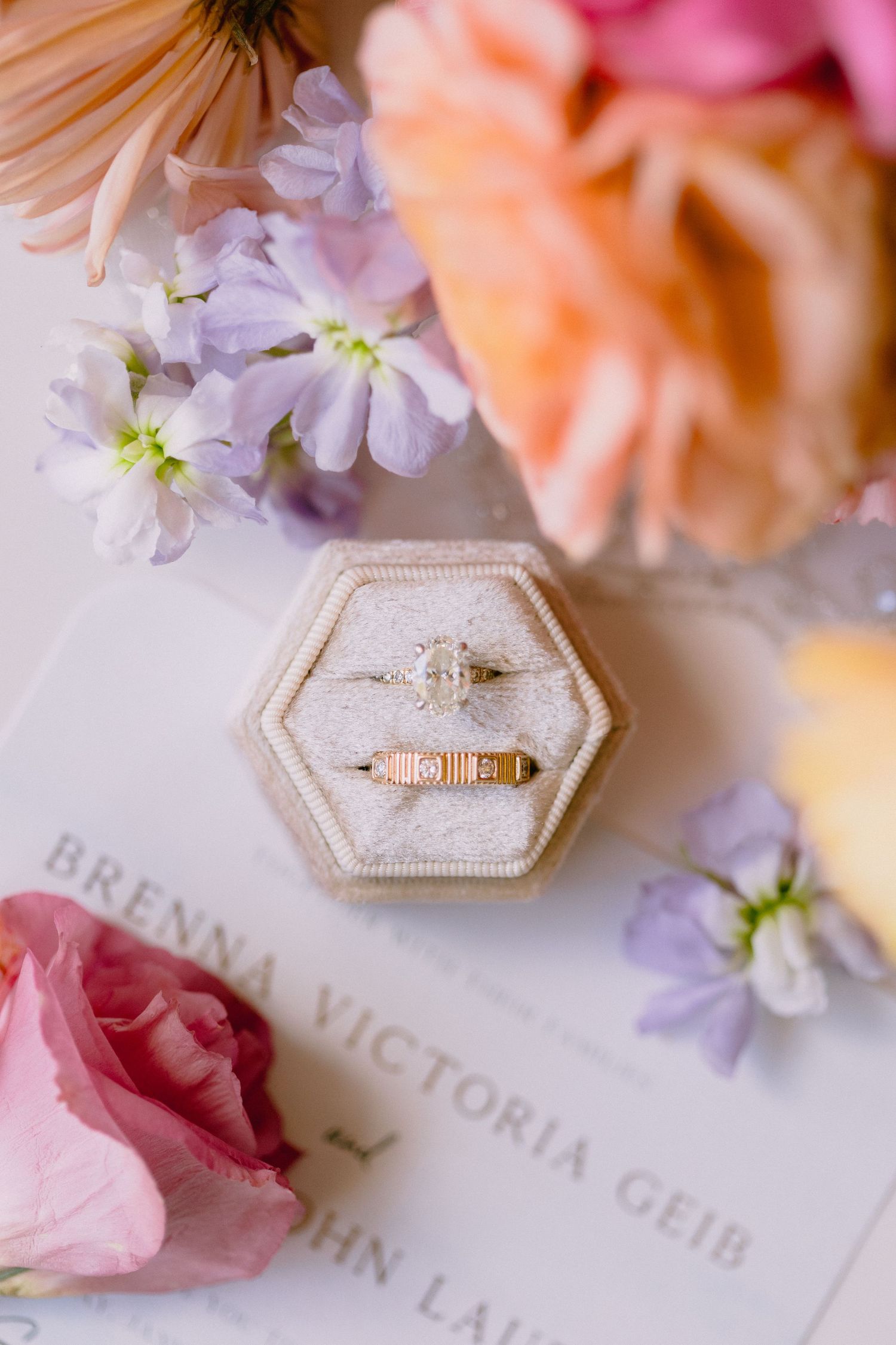 Elegant destination wedding rings in a hexagonal velvet box around tropical flowers