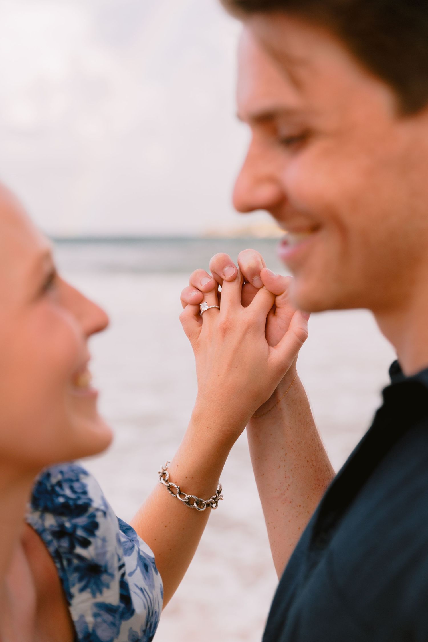 A couple holds hands intimately in a romantic moment against a light background.