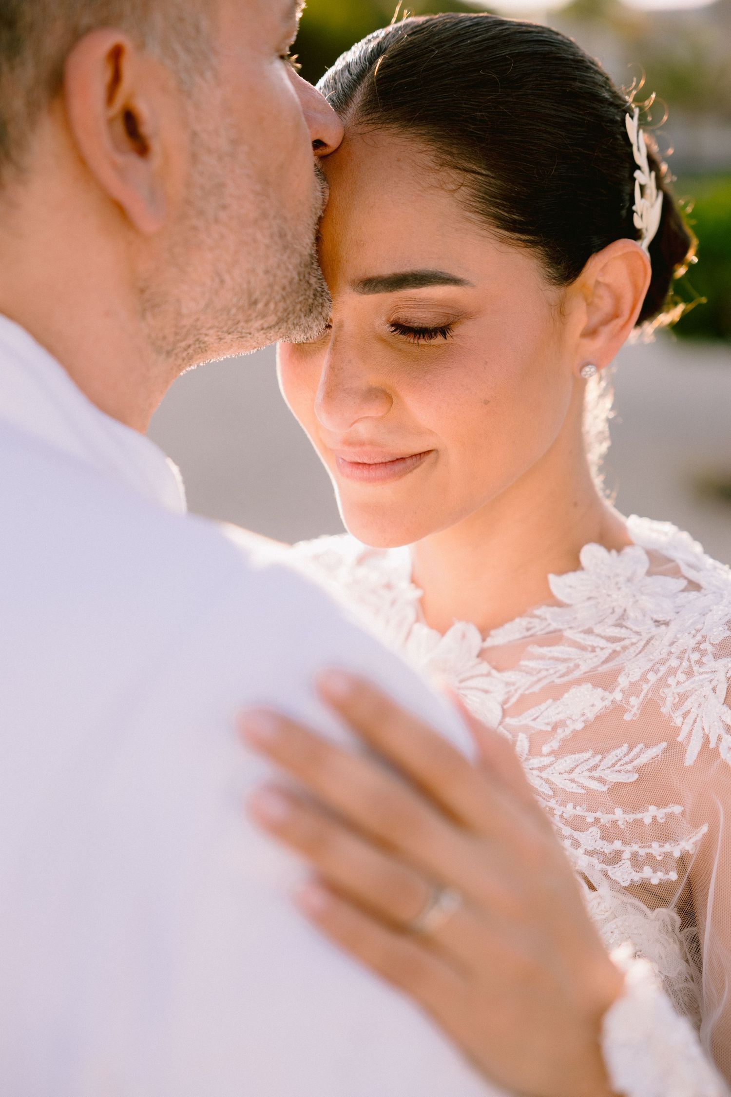 Close-up detail of delicate white lace wedding dress in soft natural lighting.