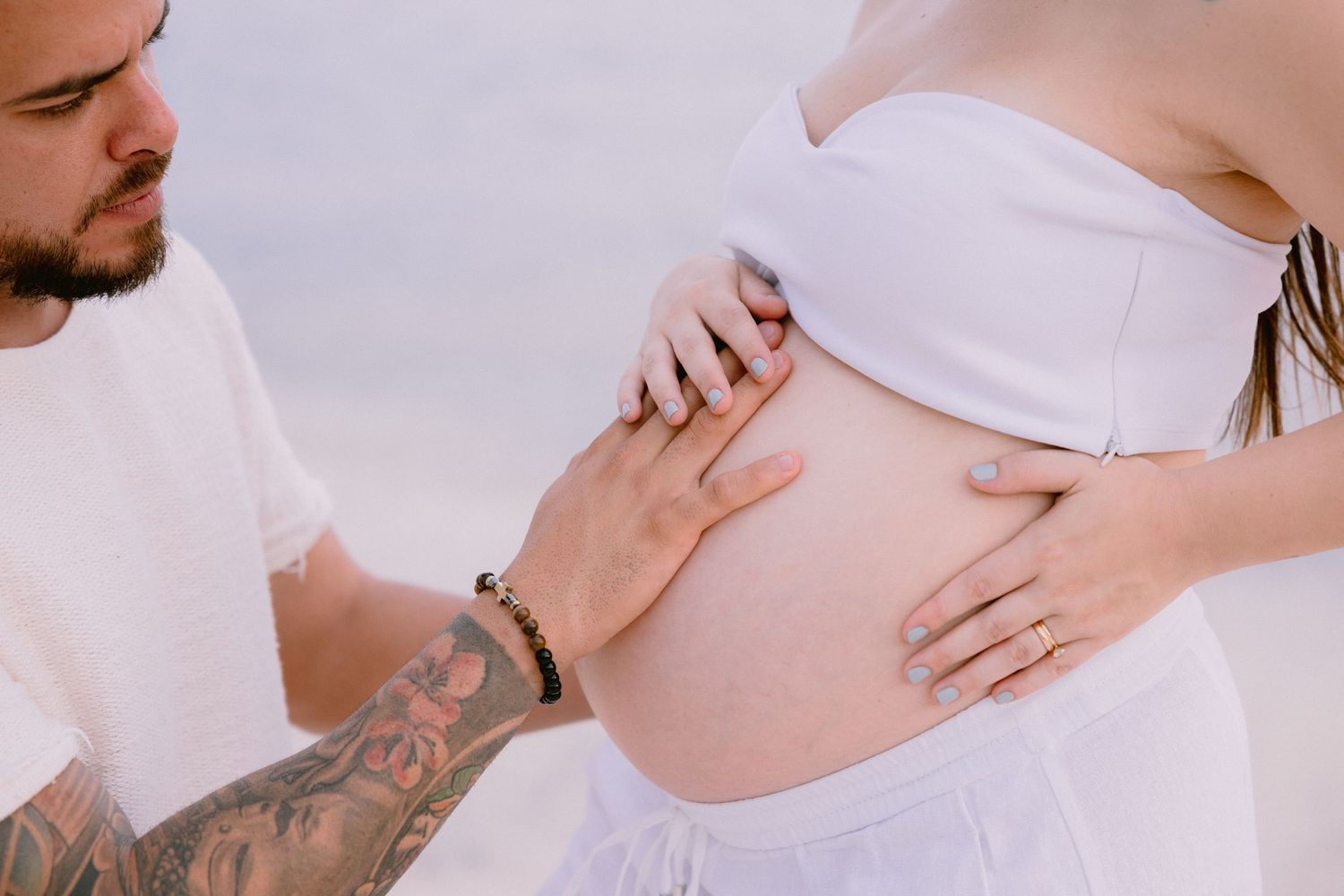 Close-up shots of people in white clothing touching and embracing, showing intimate and tender moments.