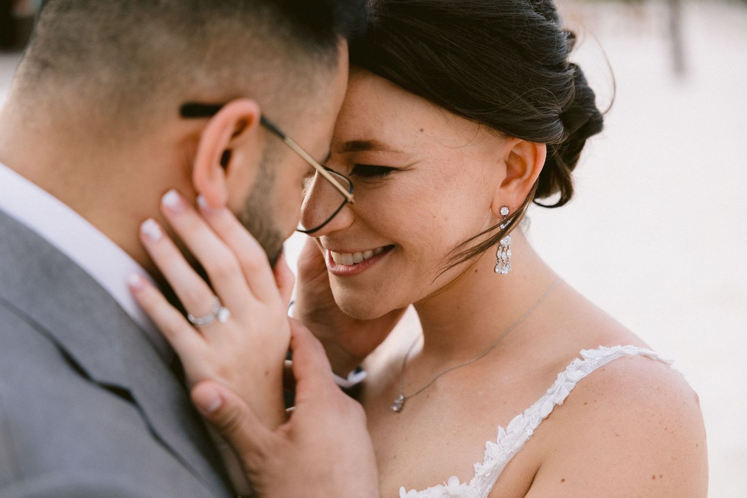 Close up view of a romantic wedding moment with delicate lace dress details and soft lighting.