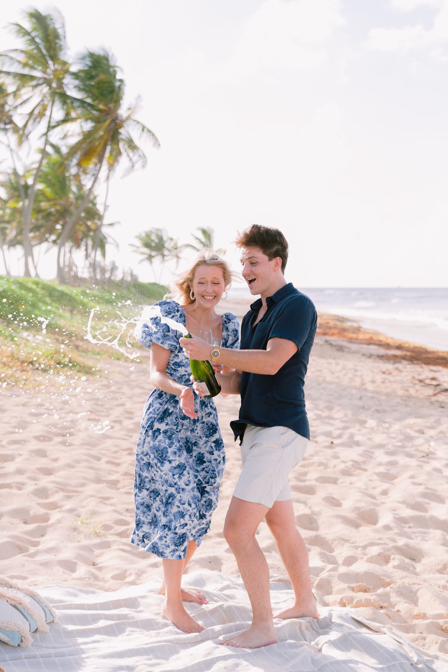Playful couple dancing and laughing together on a tropical beach.