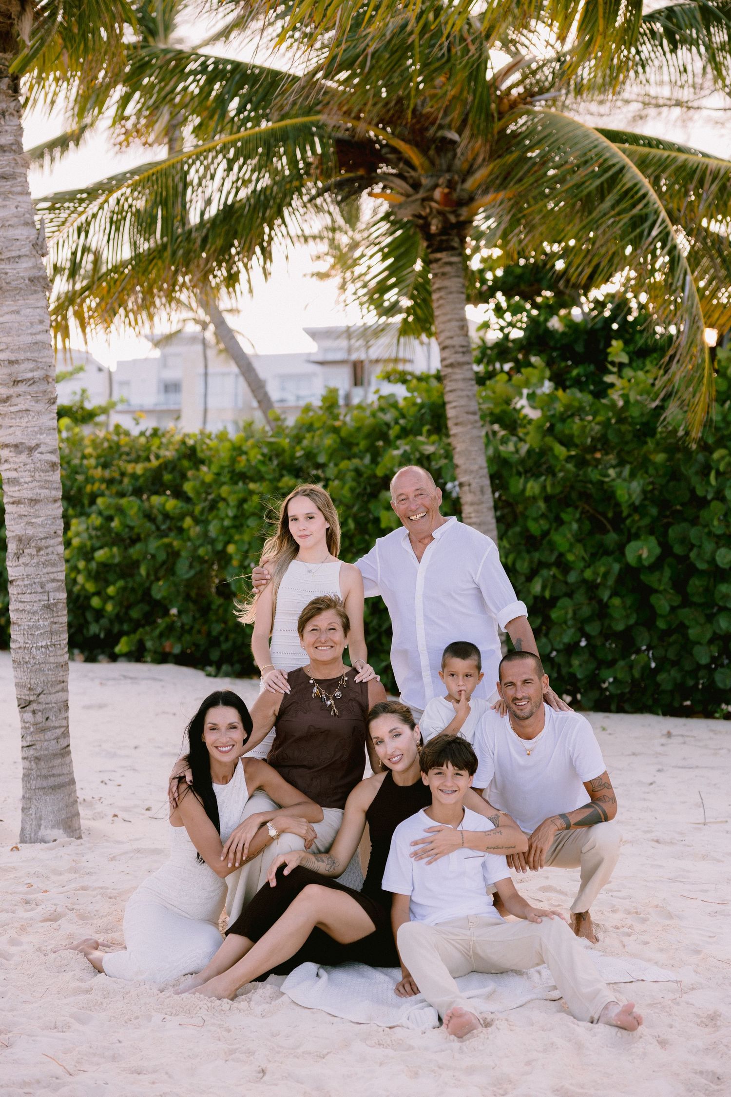 A group relaxes together on a tropical beach with palm trees and white sand.