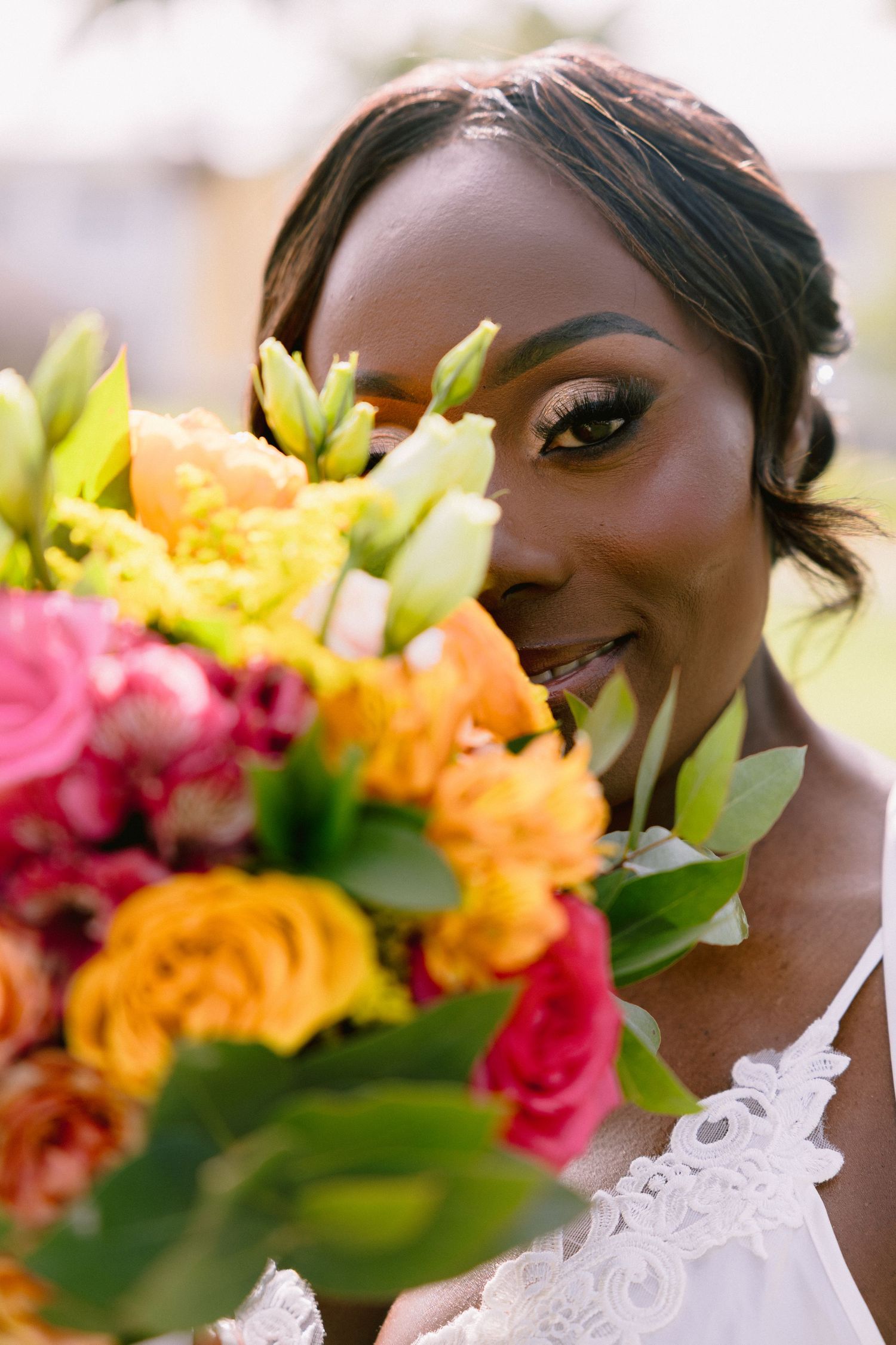 Vibrant pink and orange floral bouquet with green foliage creates a colorful wedding day arrangement.