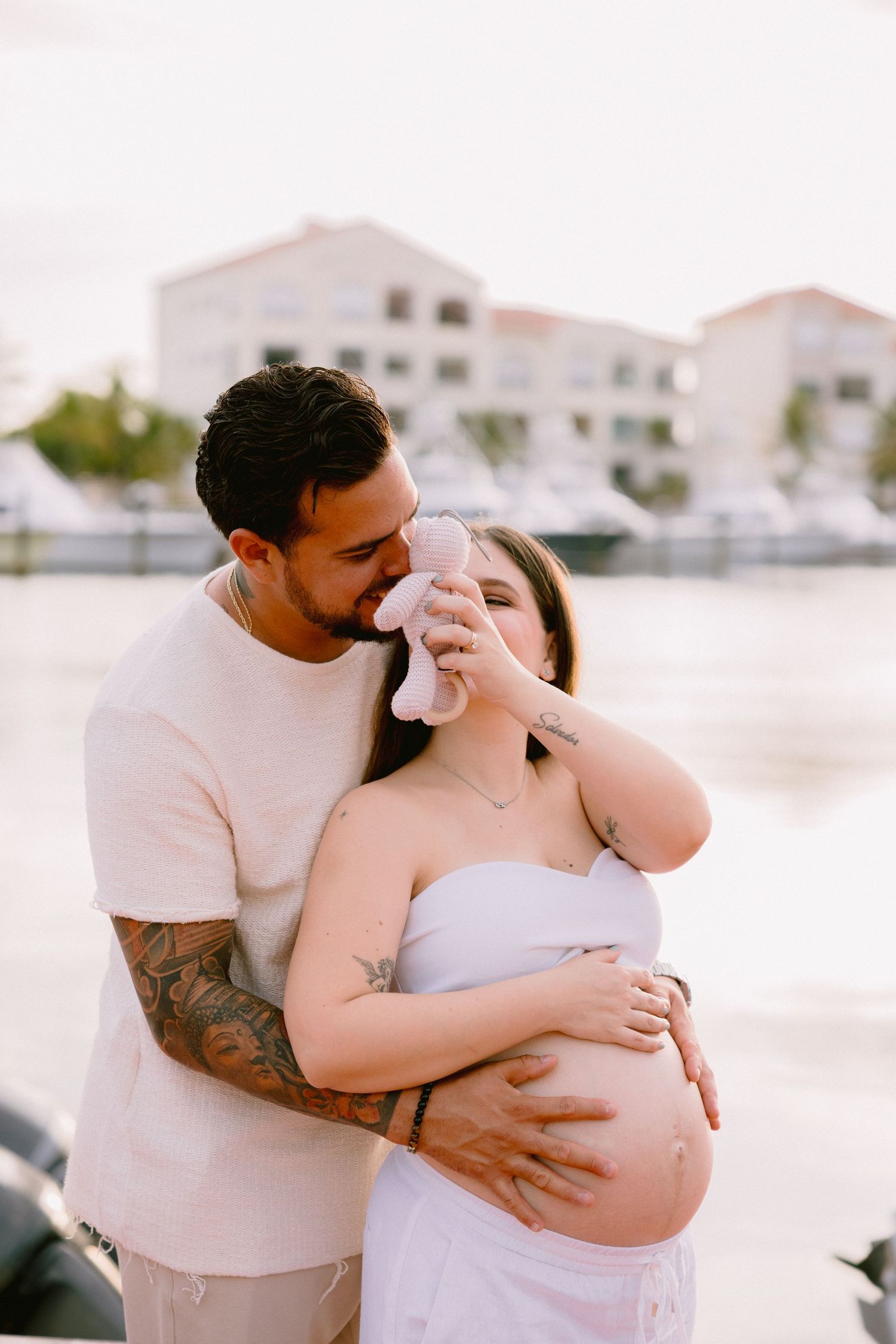 A romantic coastal photo session showing tender moments between a couple in white, captured during sunset.
