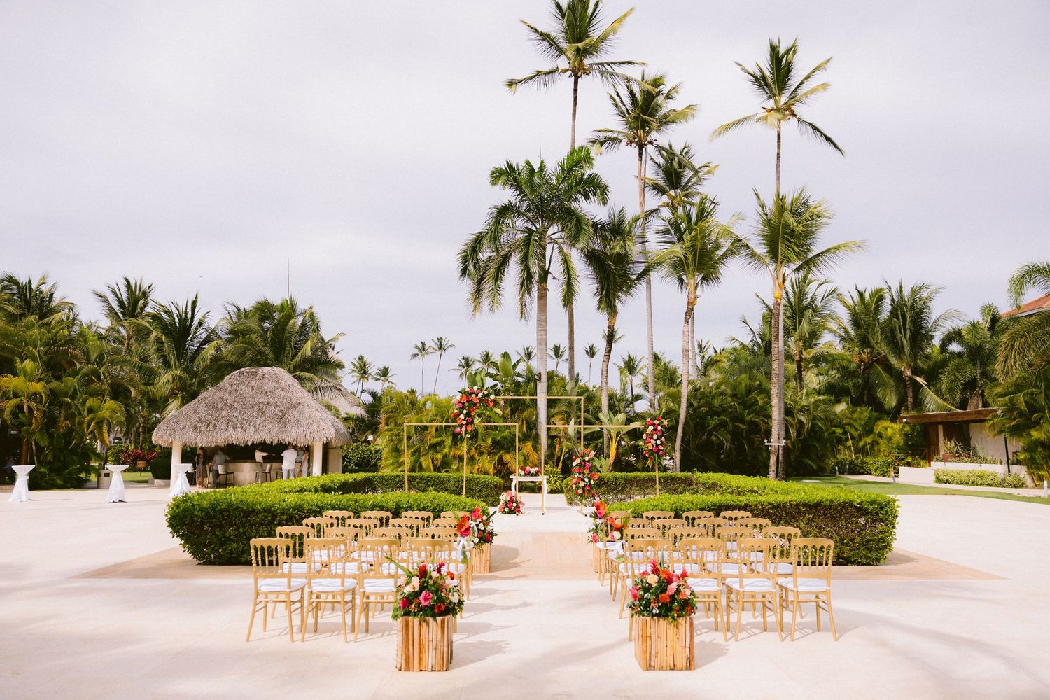 Tropical wedding ceremony setup with gold chairs and palm trees at an outdoor beach resort venue.