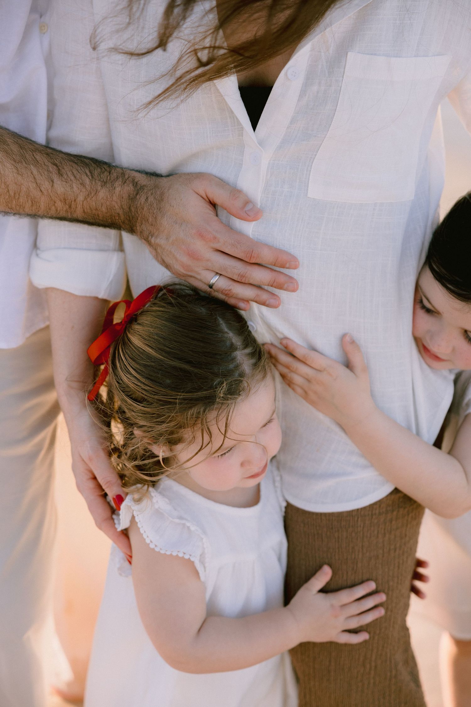 Close-up shots of a person wearing white clothing while embracing and showing affection in warm lighting.