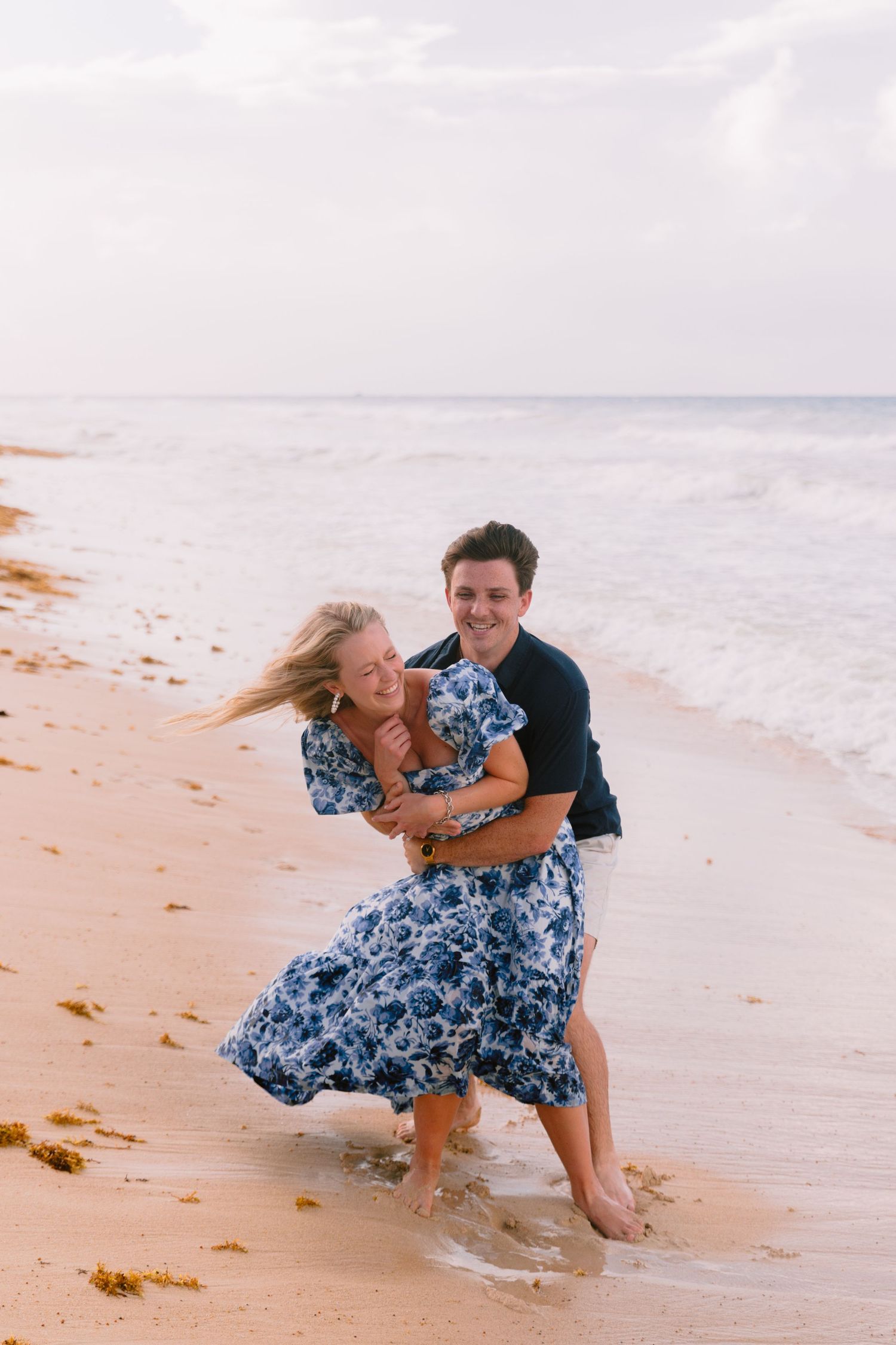 Couple playing and splashing in the waves at the beach shore.