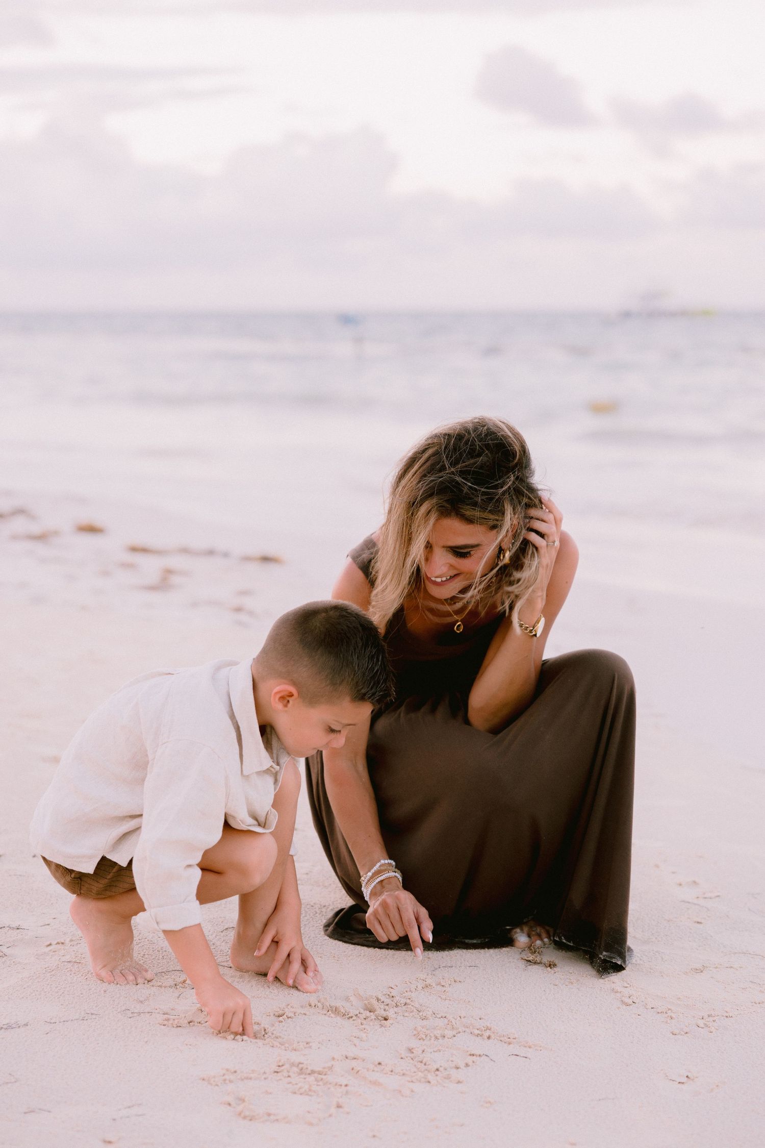 A tender moment shared between two people lying on white sand beach at sunset.