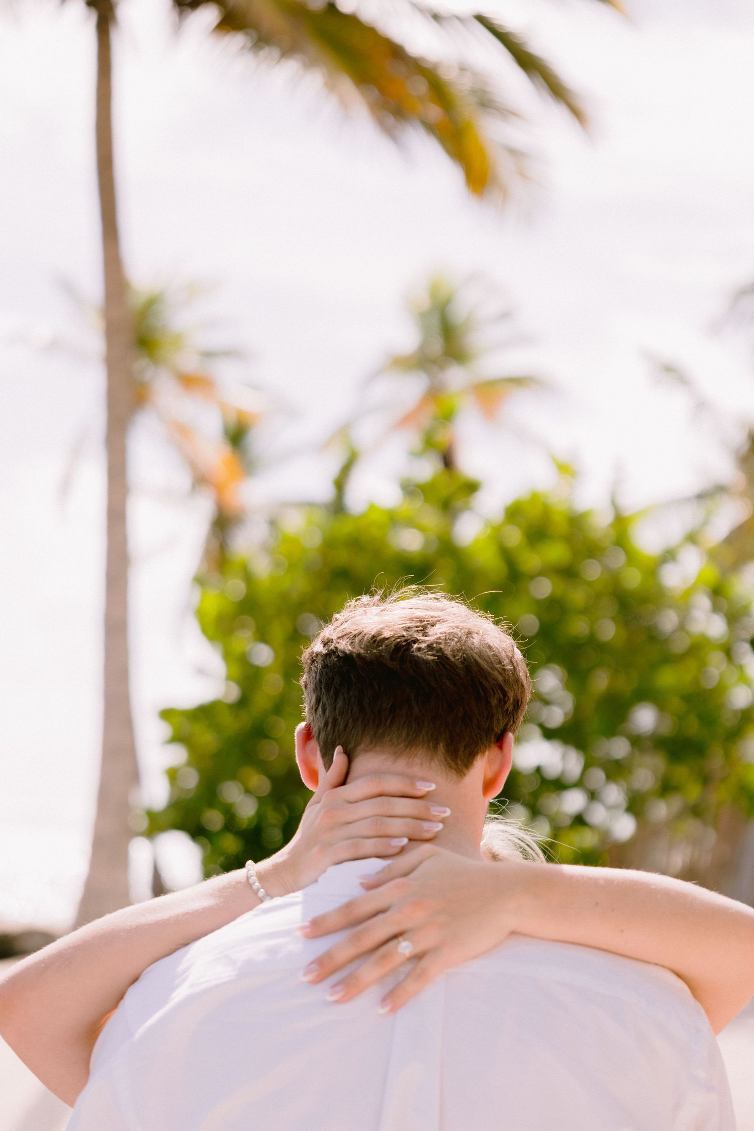 Three identical photos of someone in a white shirt from behind against a tropical palm tree background in warm sunlight.
