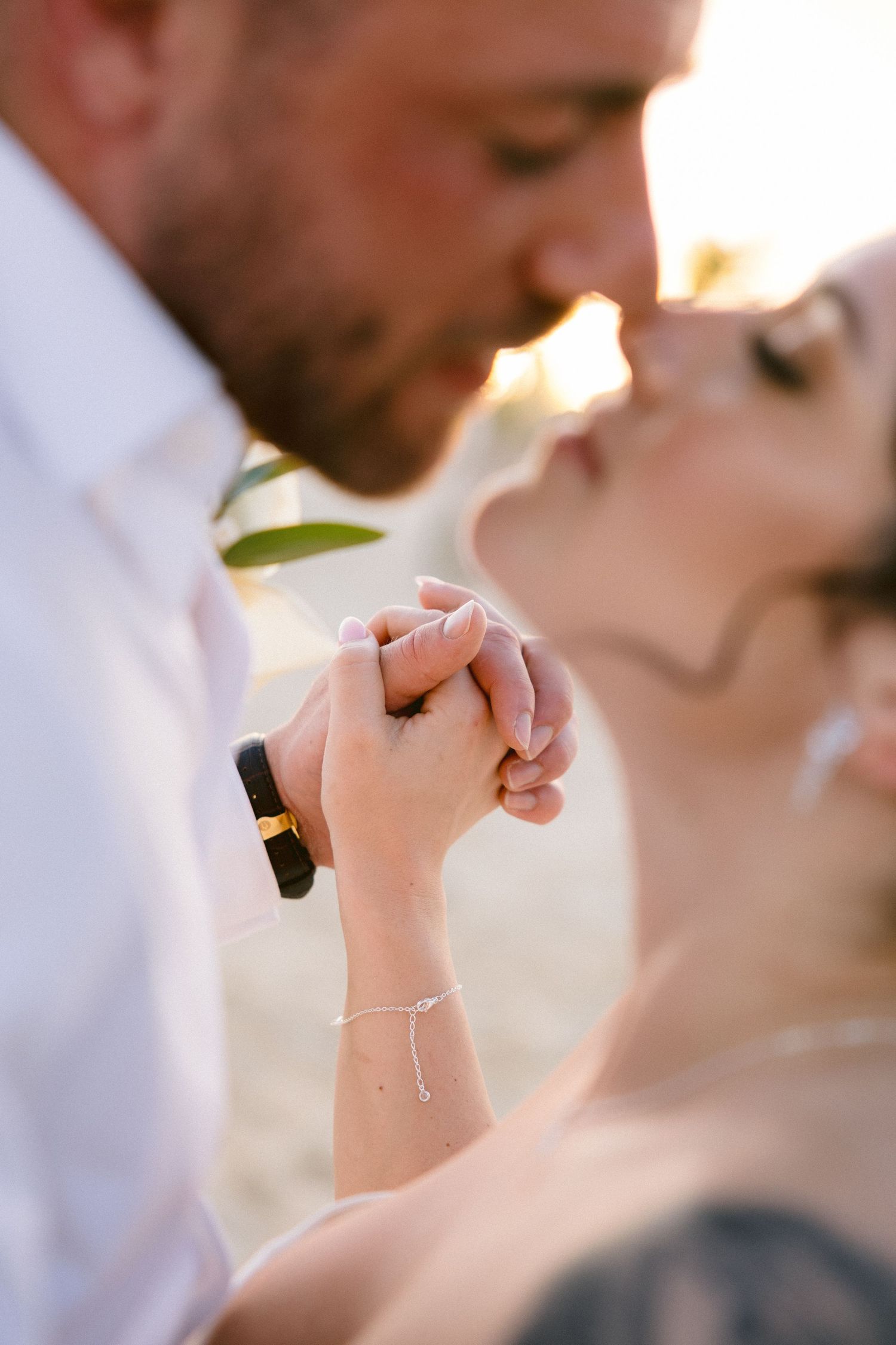 Close-up of hands clasped together at an outdoor wedding ceremony.