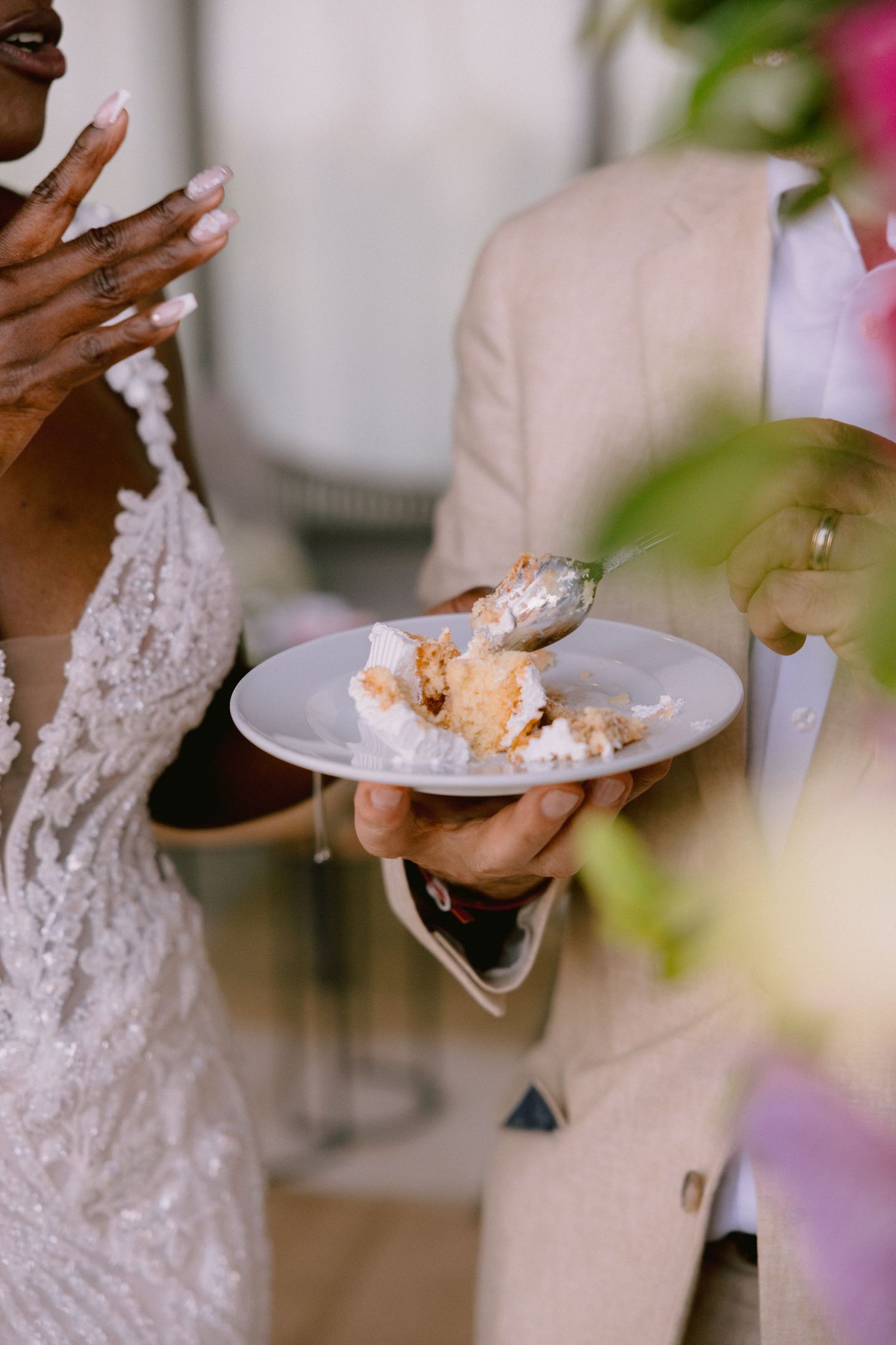 Person wearing delicate lace sleeves serves elegant slices of cake at a formal event.