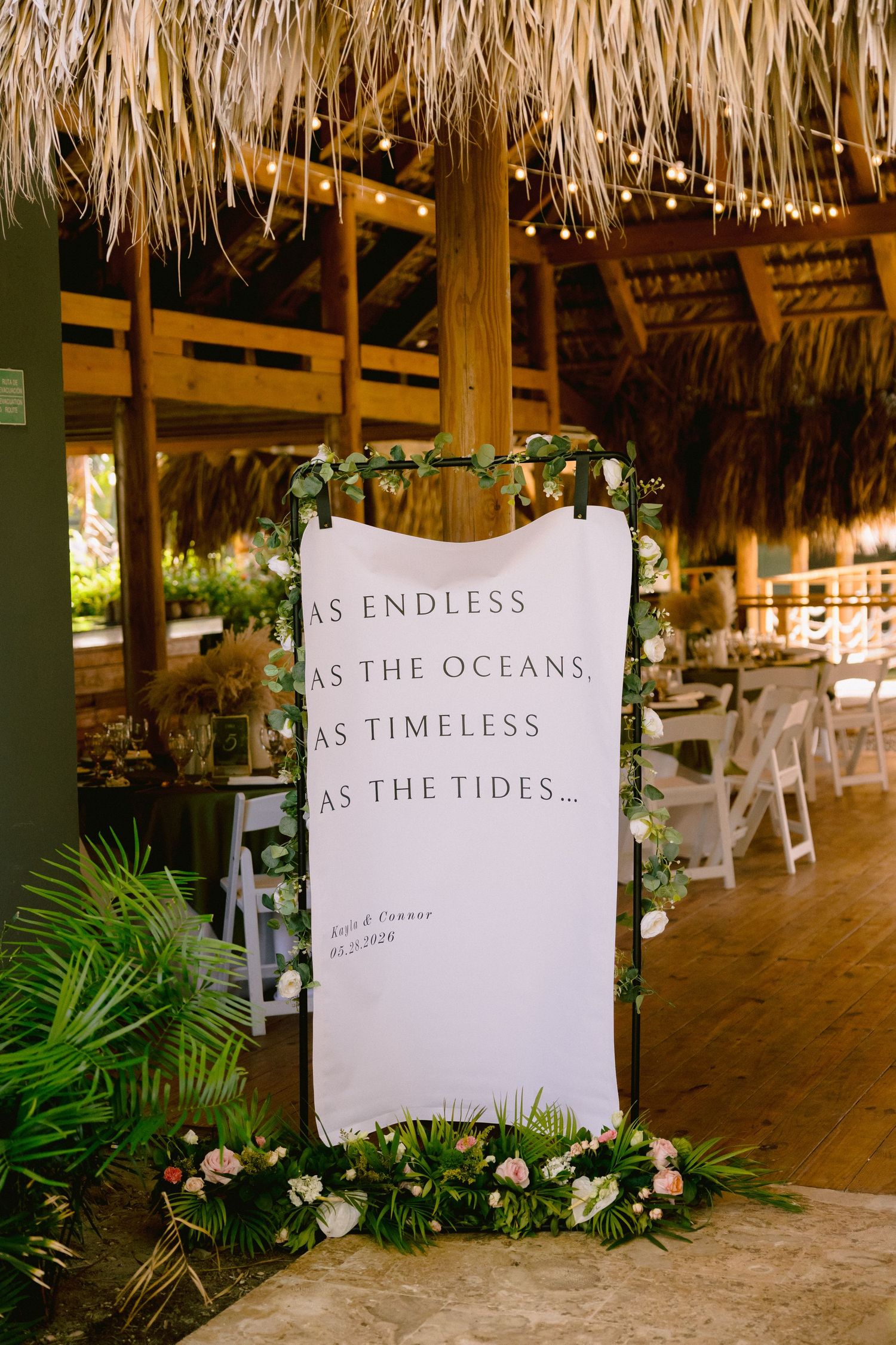 Elegant wedding venue sign reading 'As Endless As The Oceans, As Timeless As The Tides' with floral decor.