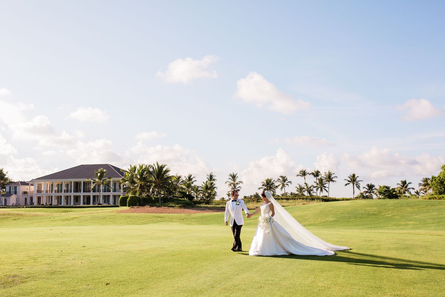 Panoramic view of a coastal golf course with palm trees, luxury homes and blue skies in Hawaii.