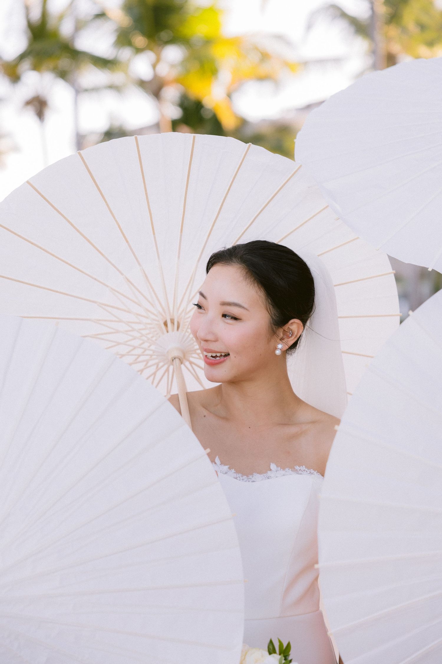 A series of photos showing a person in white holding traditional paper parasols against a bright outdoor background.