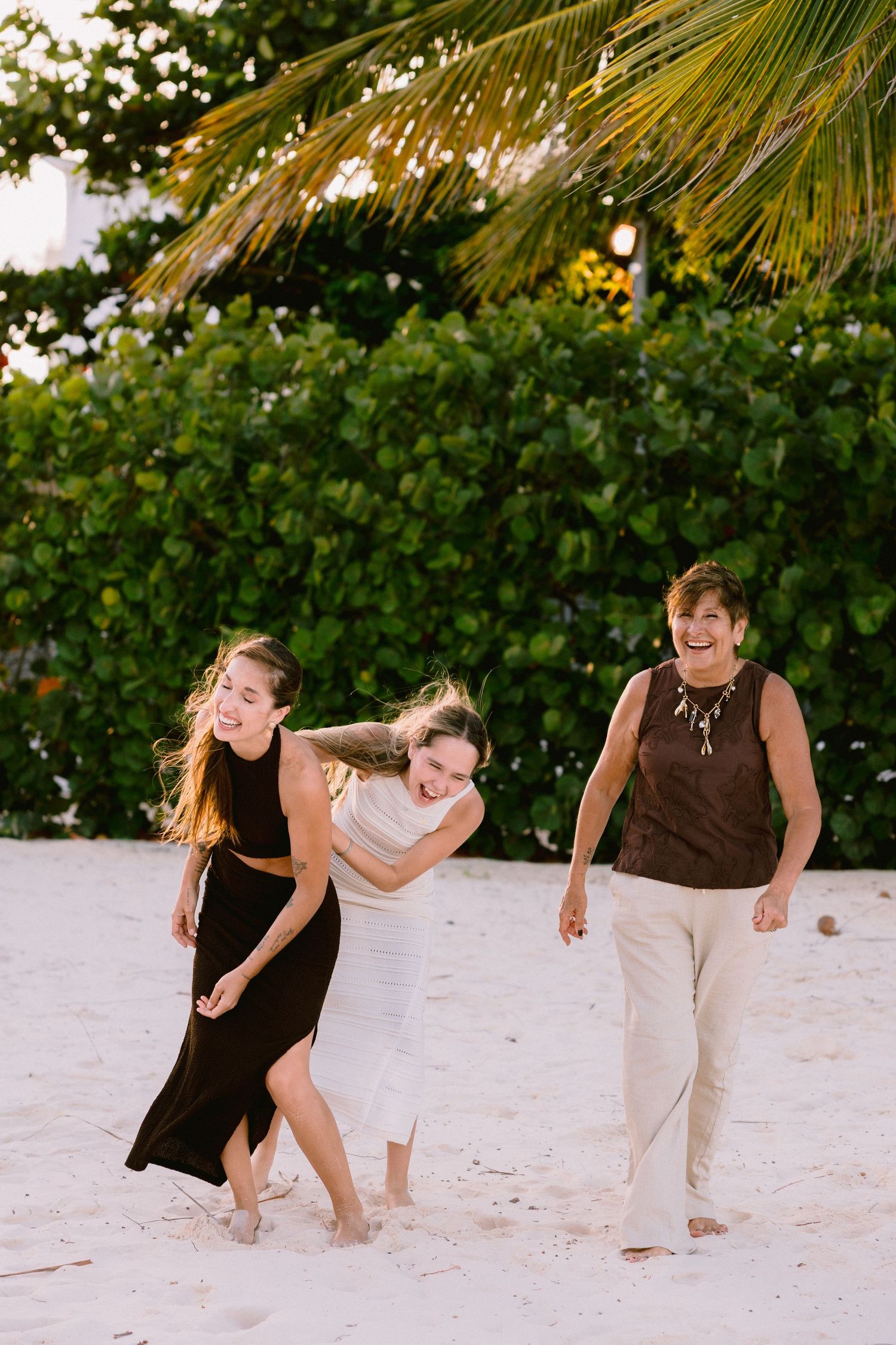 People playfully run and chase each other on a sandy beach.