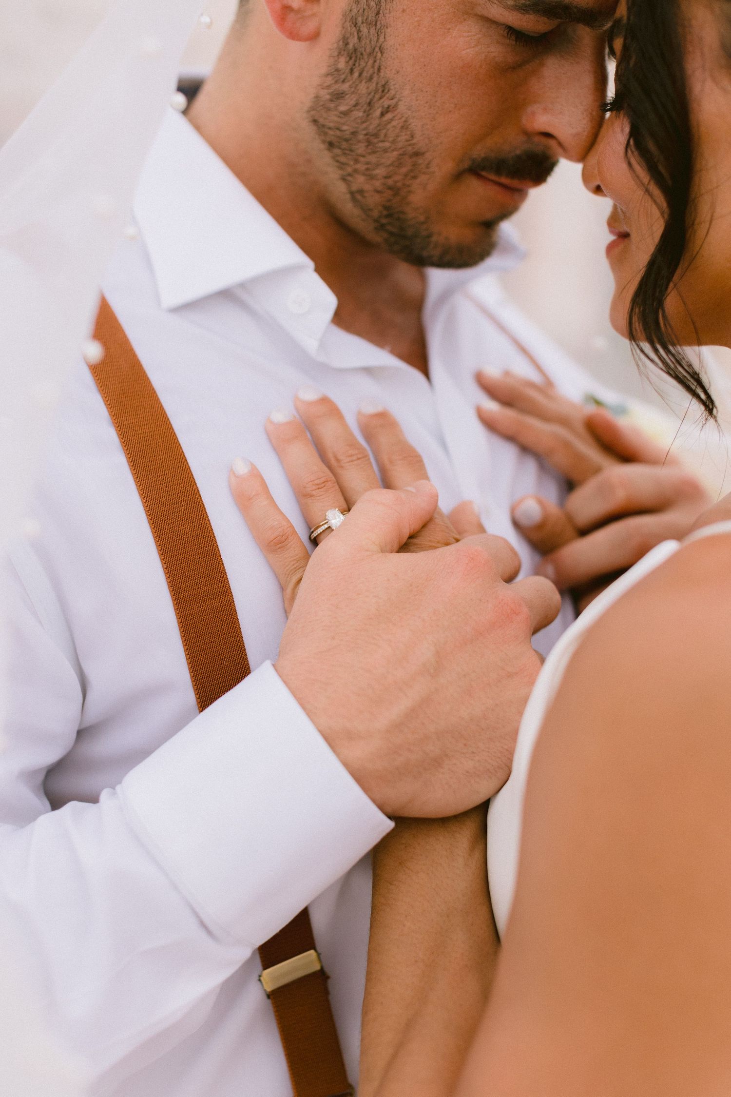 Intimate romantic moment captured between couple in white attire.