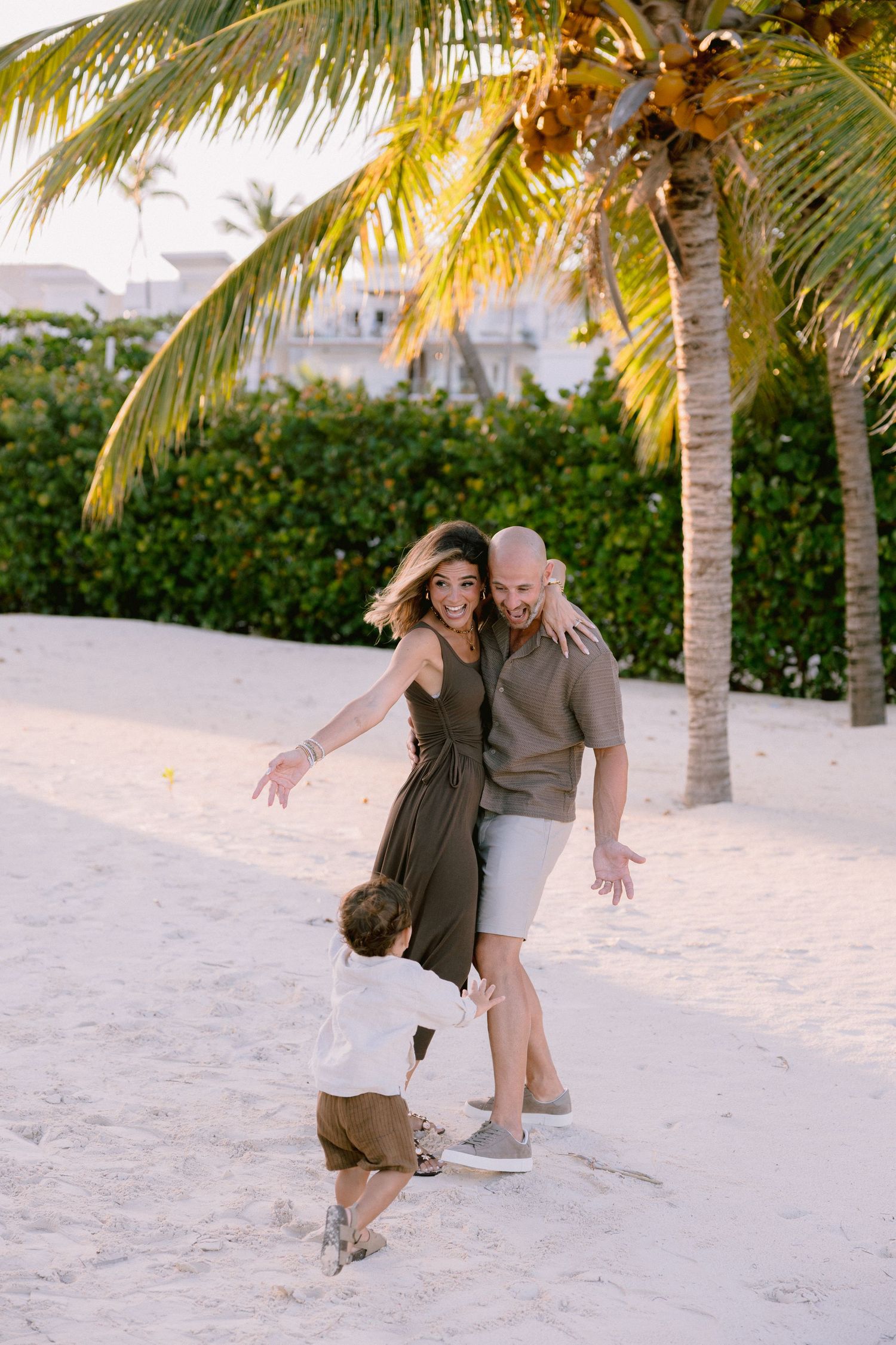 A couple shares romantic moments on a tropical beach with palm trees and white sand at sunset.